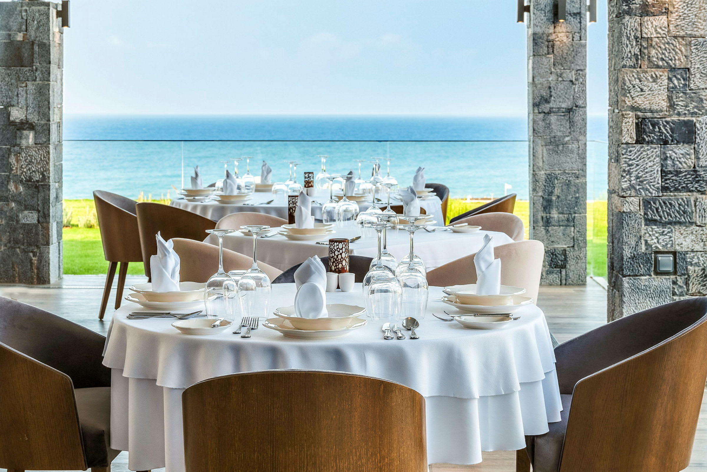 Bild på en restaurang med dukade bord, utsikt mot havet. (AI-genererad text)