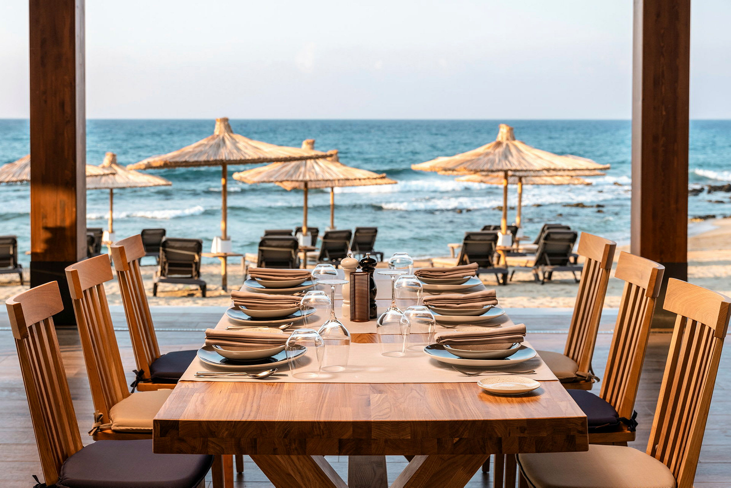 Ett dukat bord med tallrikar och glas, med utsikt över stranden och havet. (AI-genererad text)