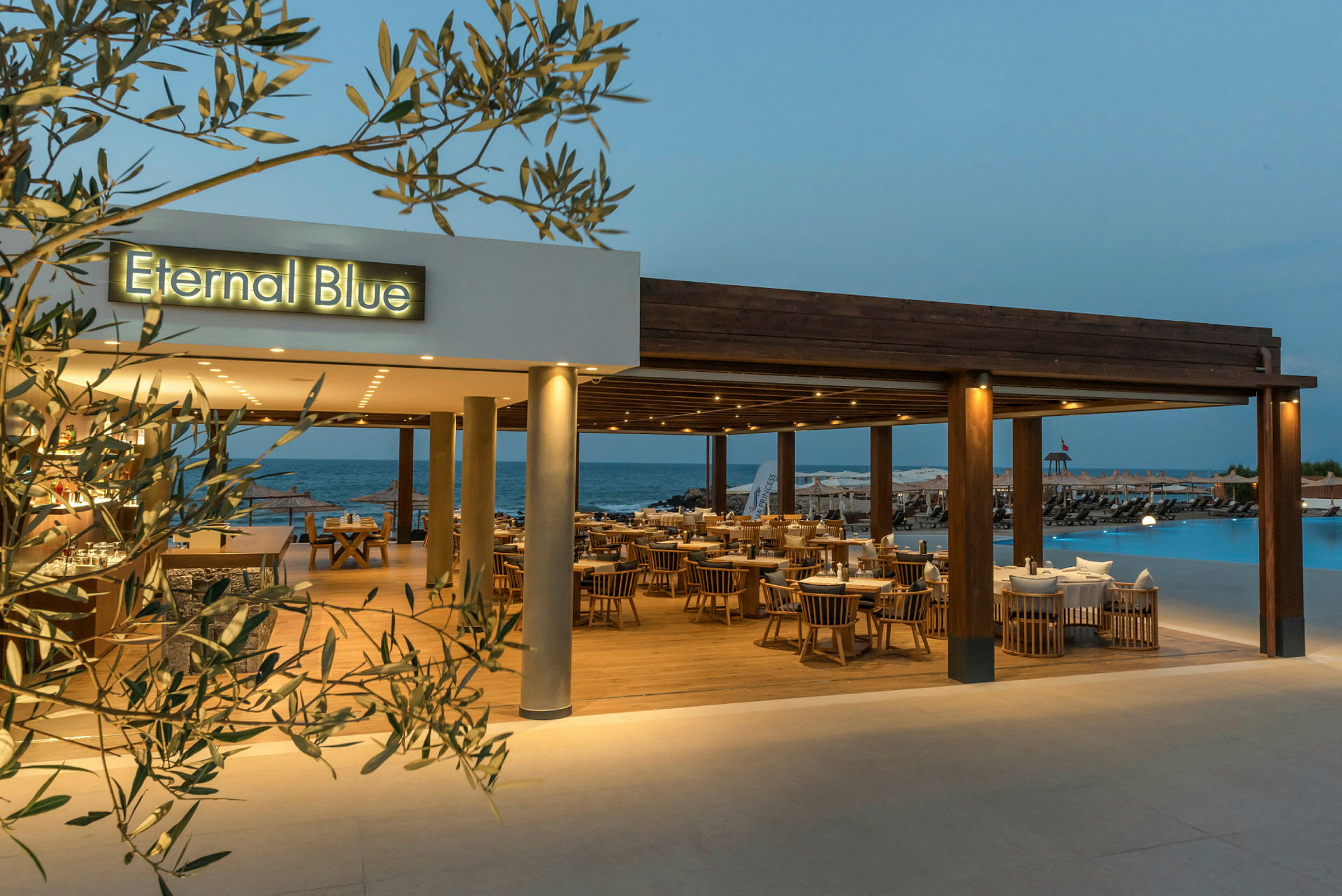 En restaurang med namnet 'Eternal Blue', med utsikt över en pool och havet i bakgrunden. (AI-genererad text)