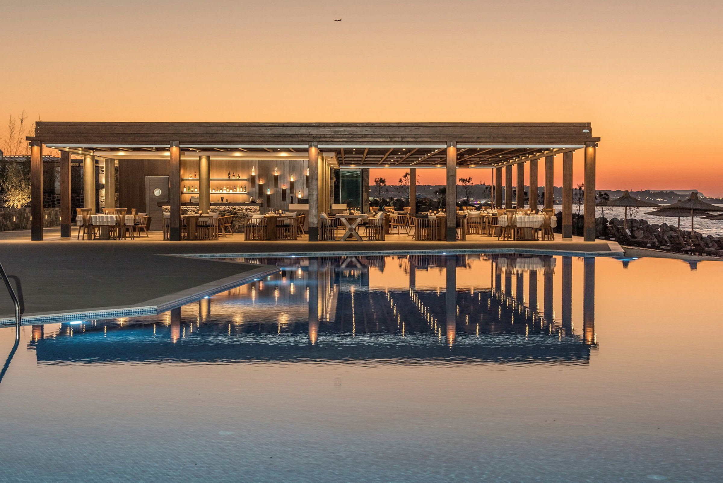 En restaurang vid en pool med solnedgång i bakgrunden. (AI-genererad text)