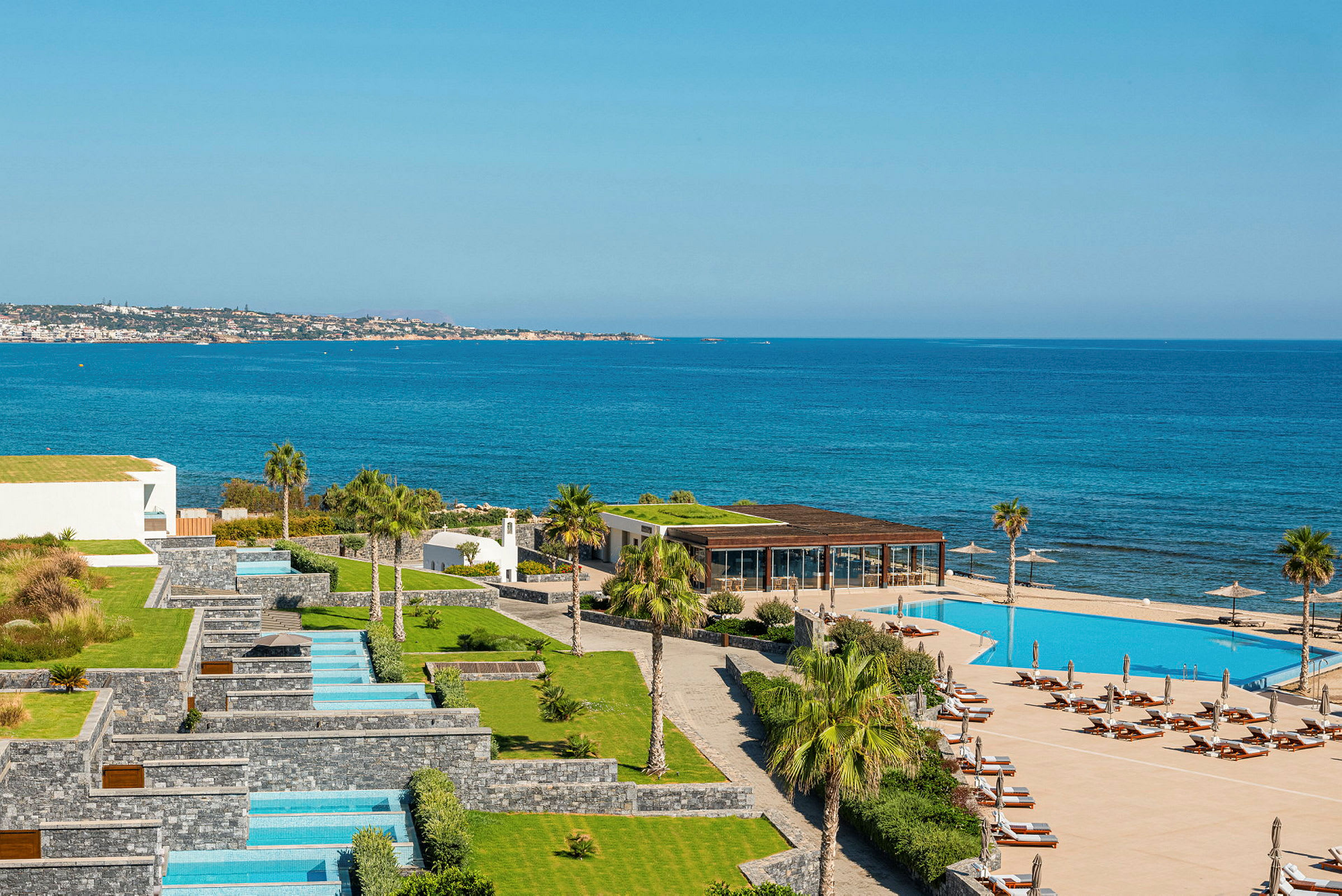 En översikt av en hotellanläggning med flera pooler och utsikt över havet. (AI-genererad text)