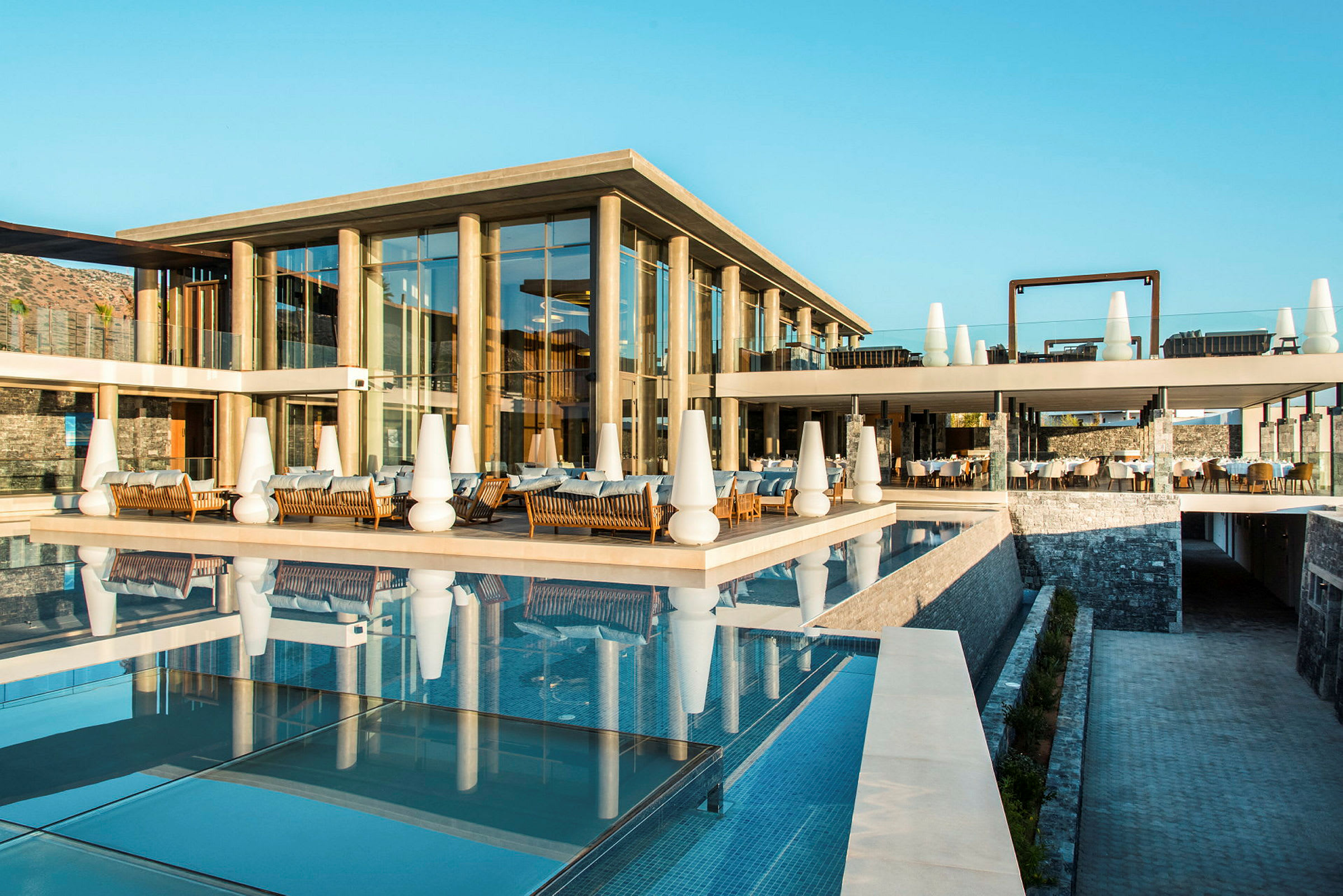 Hotellbyggnad med glassfasad och pool. (AI-genererad text)