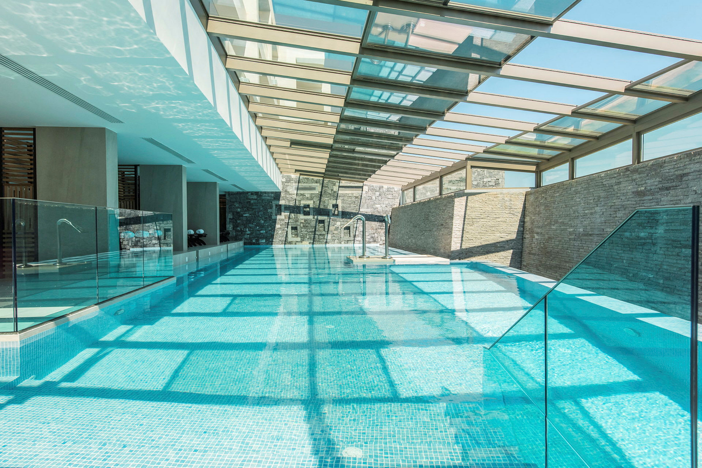 En lång pool inomhus med glastak som släpper in ljus. (AI-genererad text)