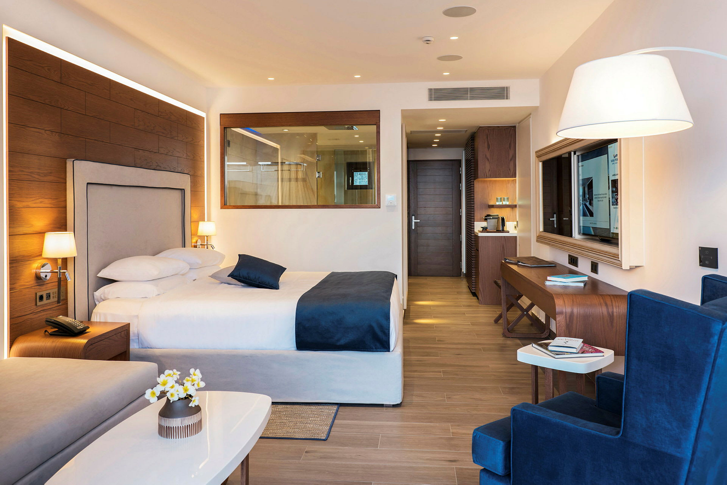 Hotellrum med en dubbelsäng, sittgrupp och arbetsbord, modernt inrett med trägolv. (AI-genererad text)