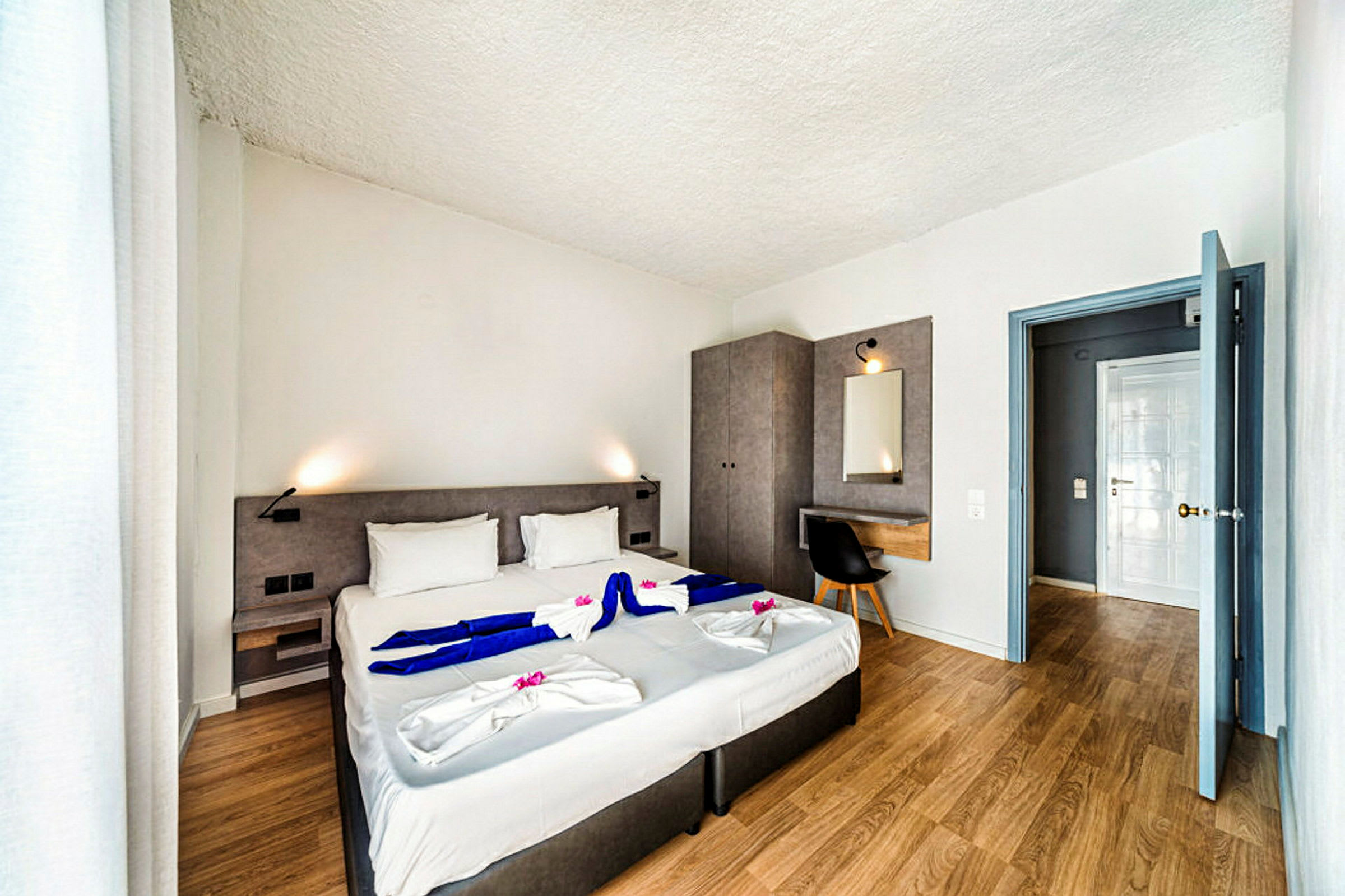 Modernt hotellrum med dubbelsäng, skrivbord och garderob. (AI-genererad text)
