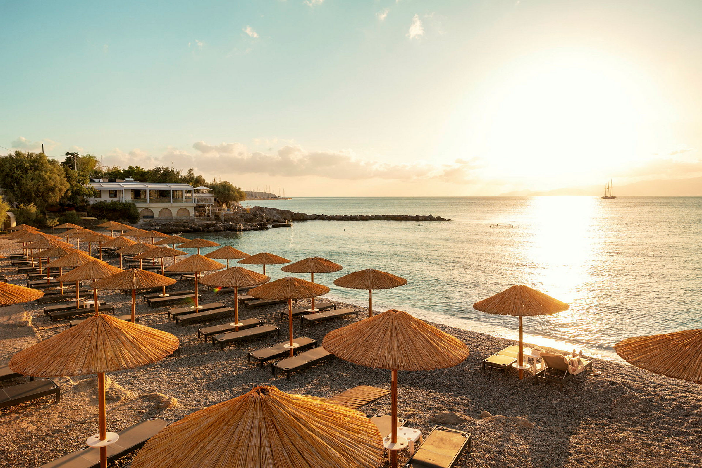 Soluppgång över en strand med solstolar och parasoller i förgrunden. (AI-genererad text)