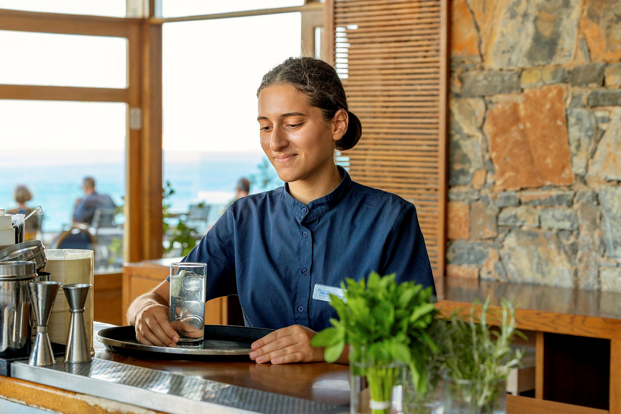 En person står vid en bar och håller i ett glas med isvatten. (AI-genererad text)