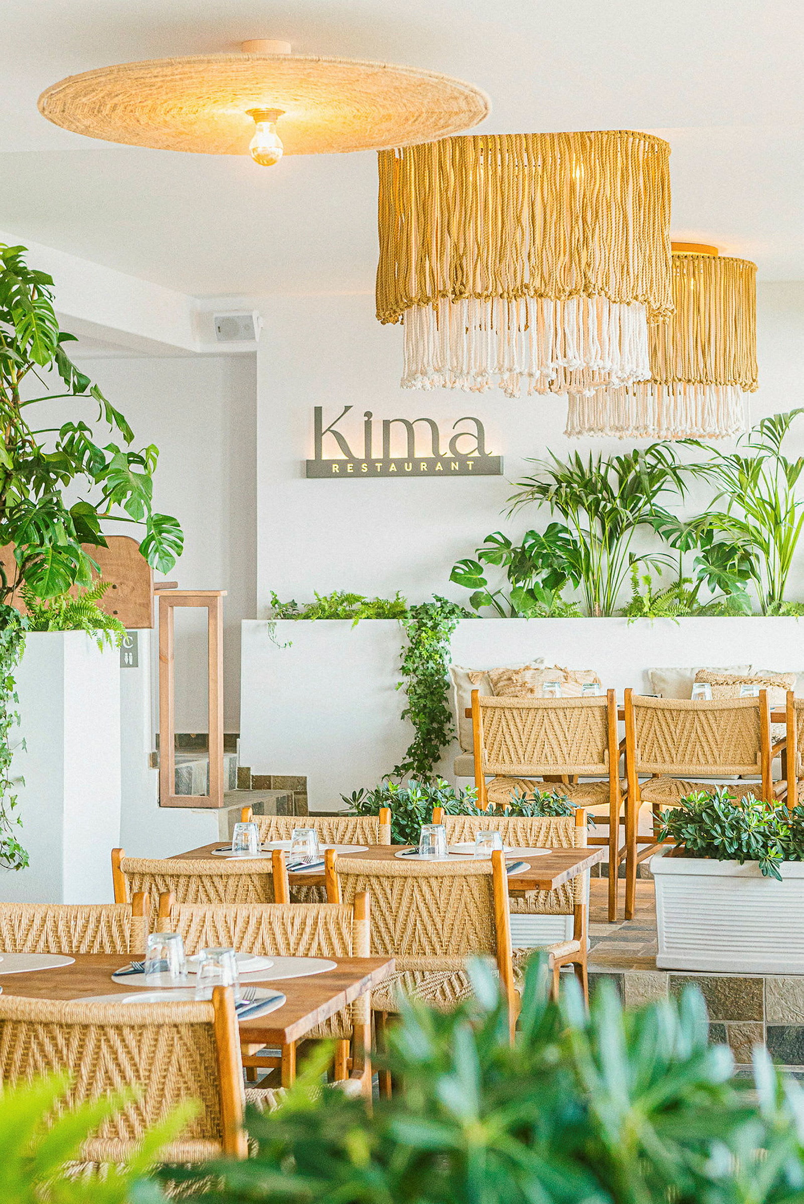 Bild av inredningen på en restaurang med gröna växter och rottinginspirerade möbler. (AI-genererad text)