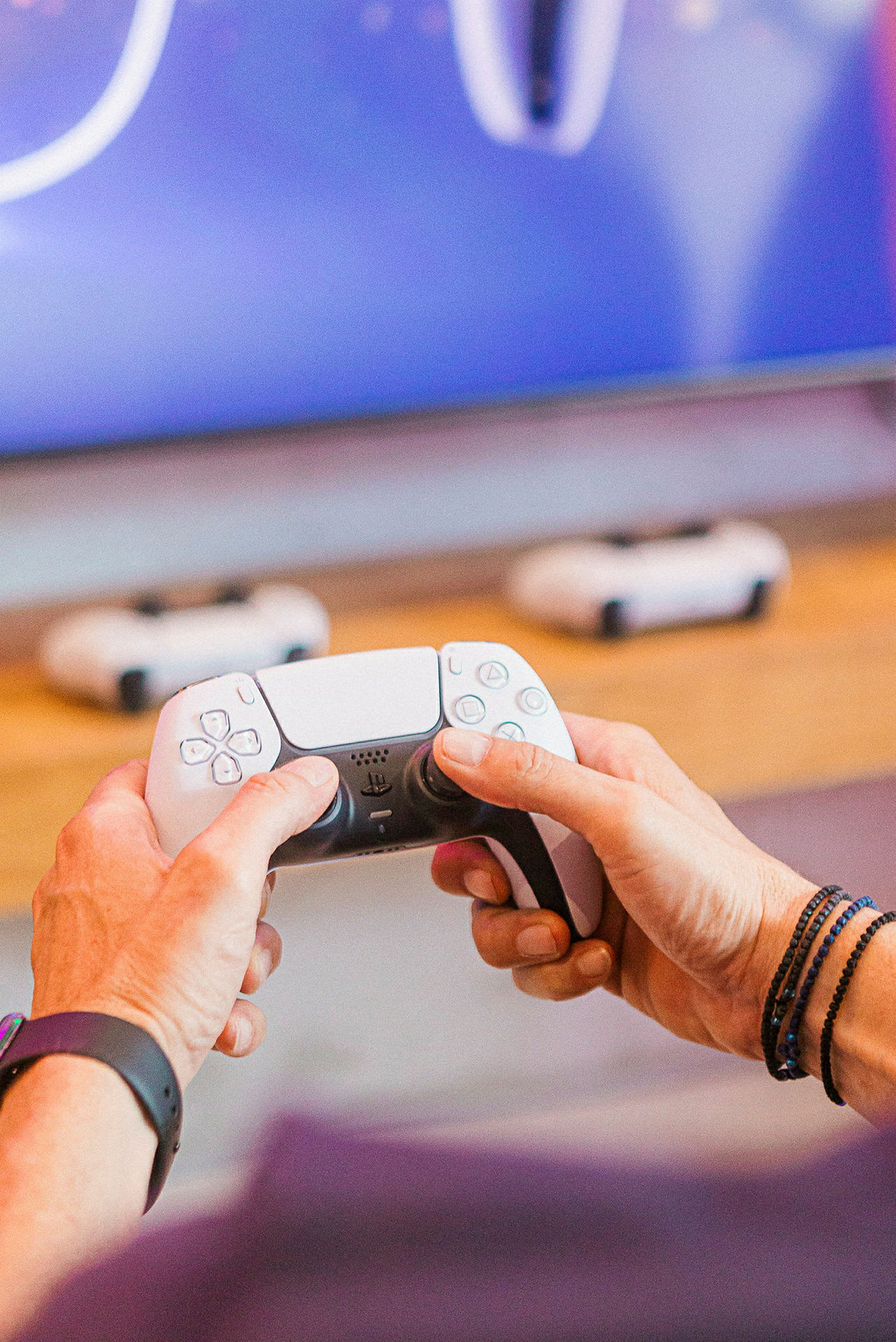 Händer håller en vit spelkontroll framför en skärm. (AI-genererad text)