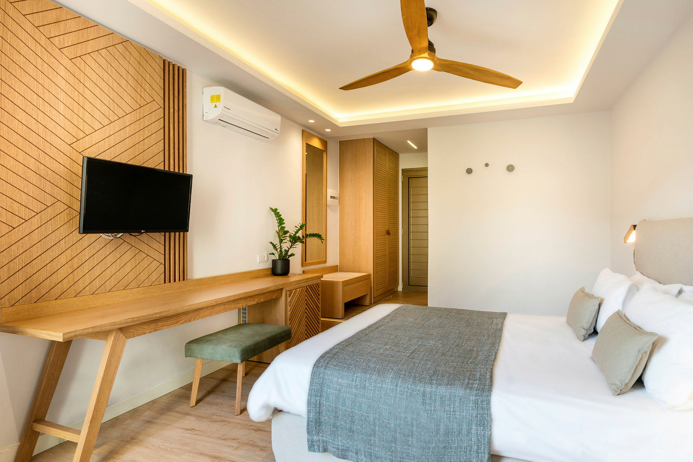 Ett hotellrum med en dubbelsäng, trädetaljer i inredningen, en väggmonterad TV och ett skrivbord. (AI-genererad text)
