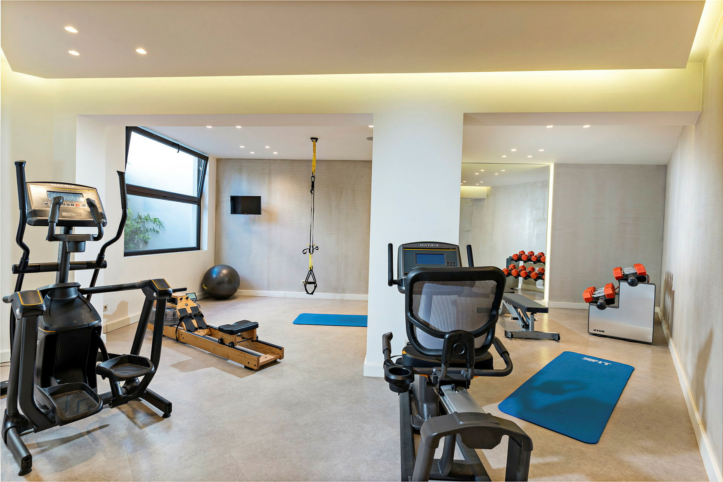 Ett gym med träningsutrustning, inklusive konditionsmaskiner, vikter och träningsmattor. (AI-genererad text)
