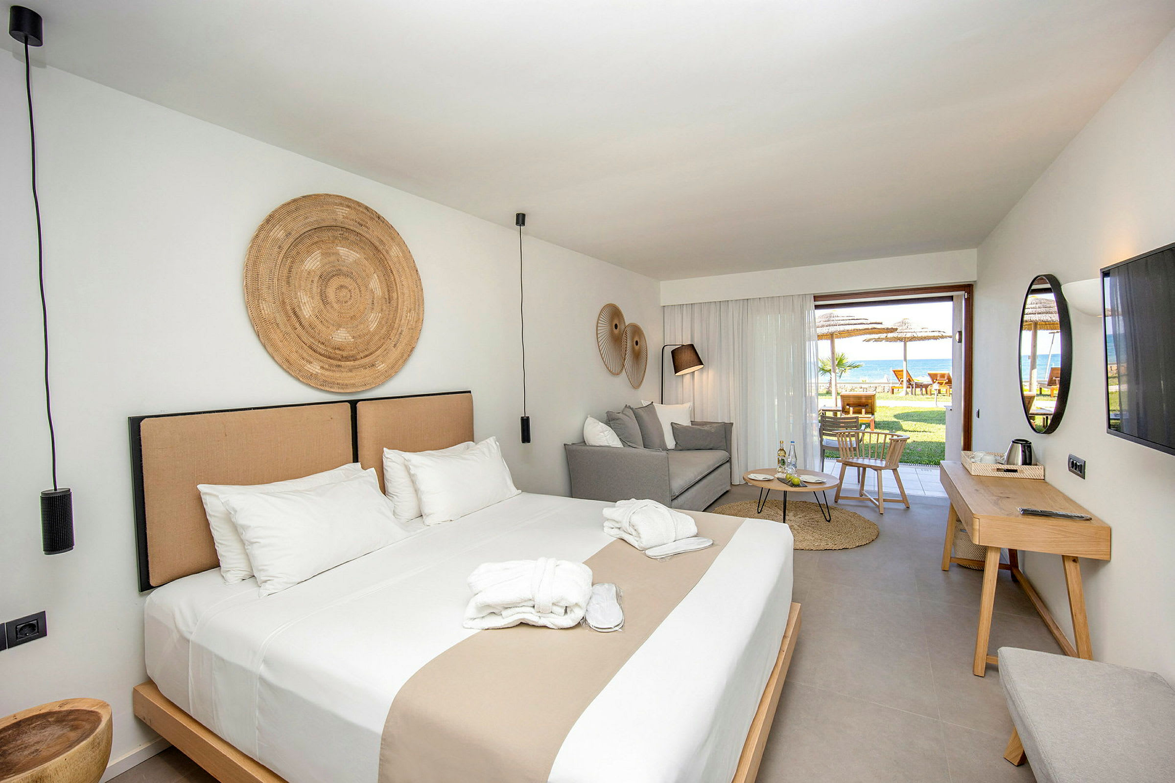 En hotellsvit med en dubbelsäng, sittplats och utgång till en möblerad uteplats. (AI-genererad text)