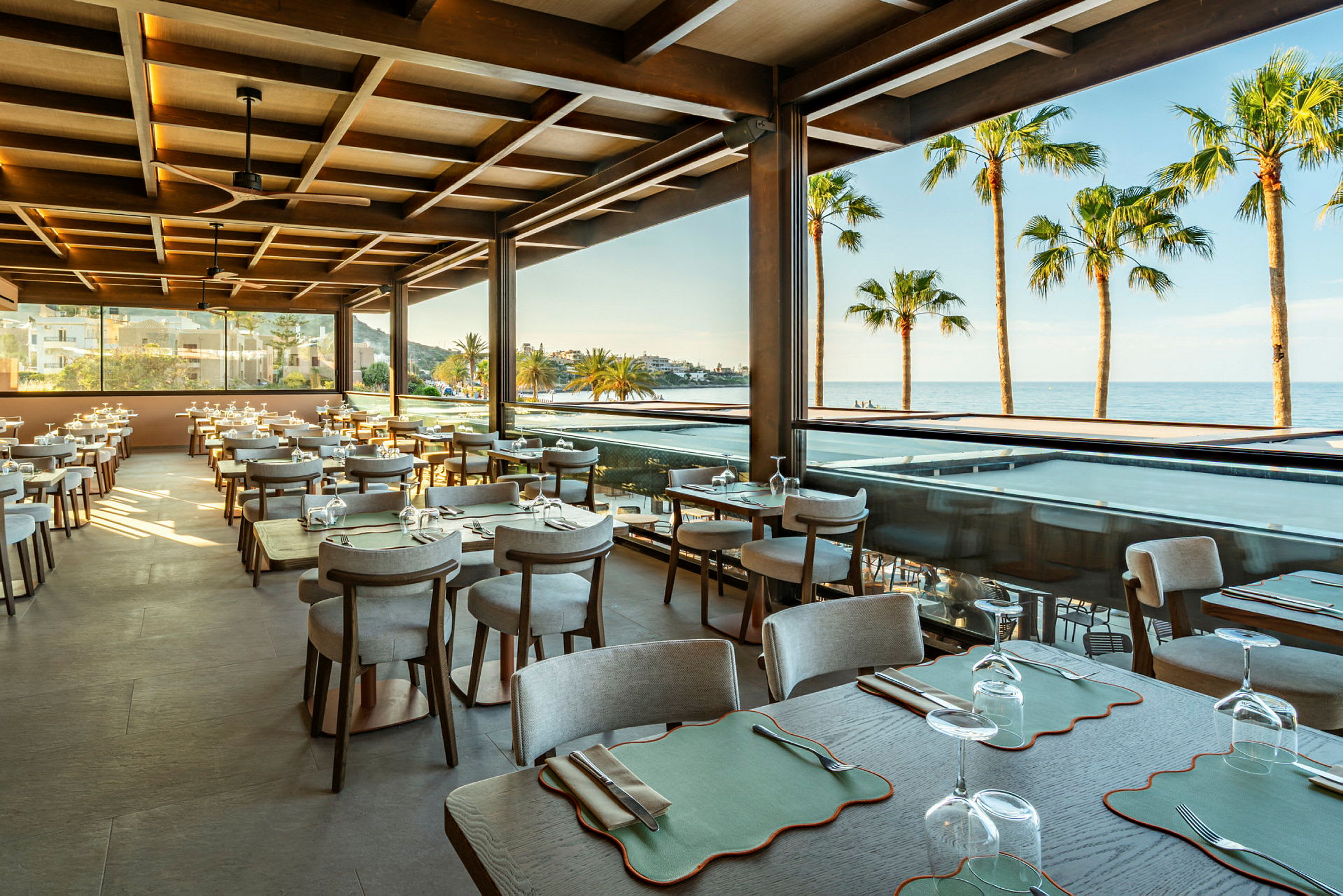Restaurang med sittplatser, utsikt mot hav och palmer. (AI-genererad text)