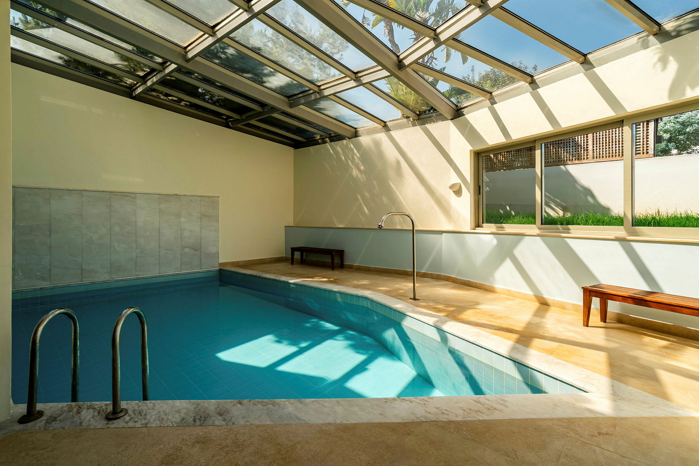 Inomhuspool med glasväggar och tak som släpper in naturligt ljus. (AI-genererad text)