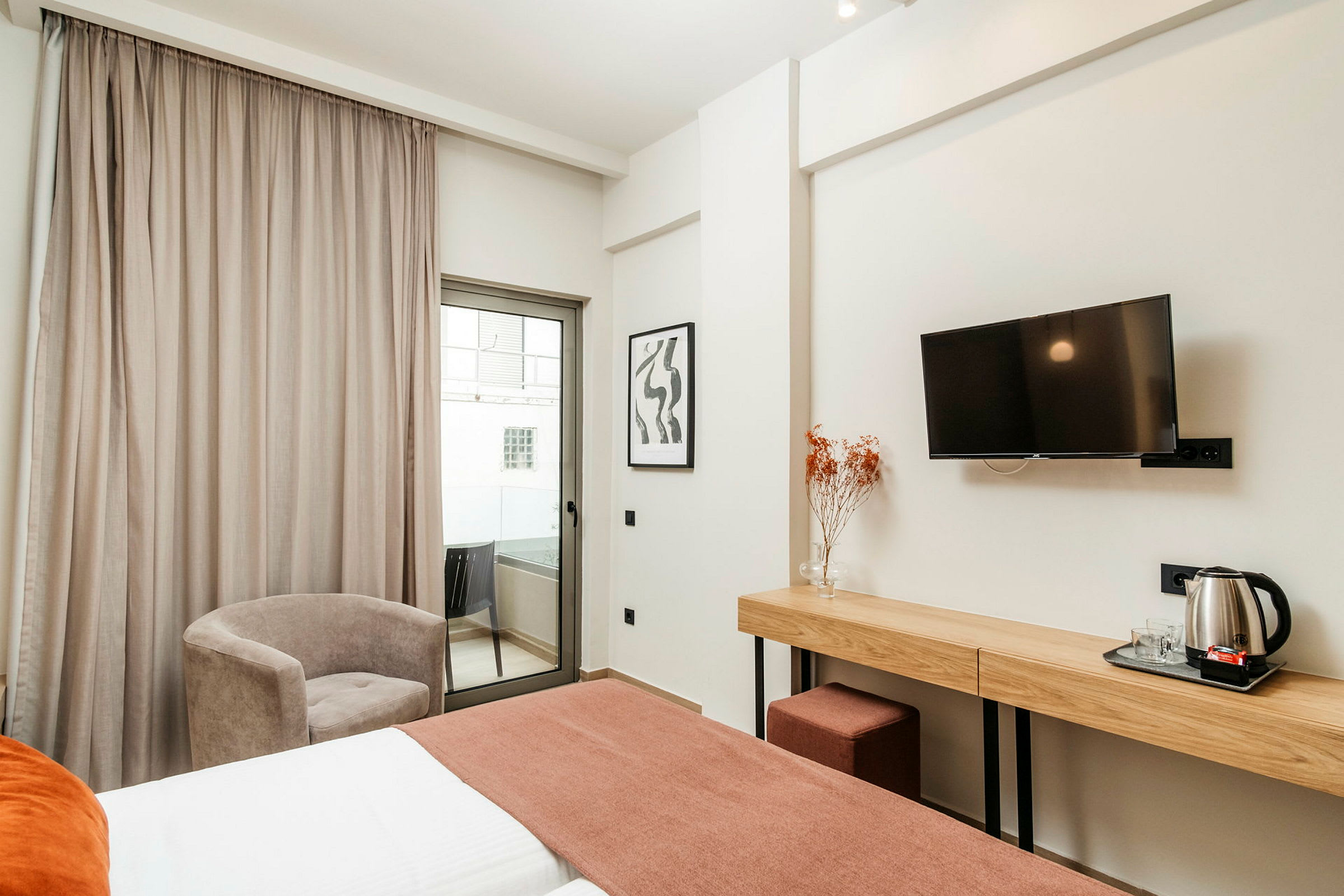 Hotellrum med säng, skrivbord, stol och balkong. (AI-genererad text)
