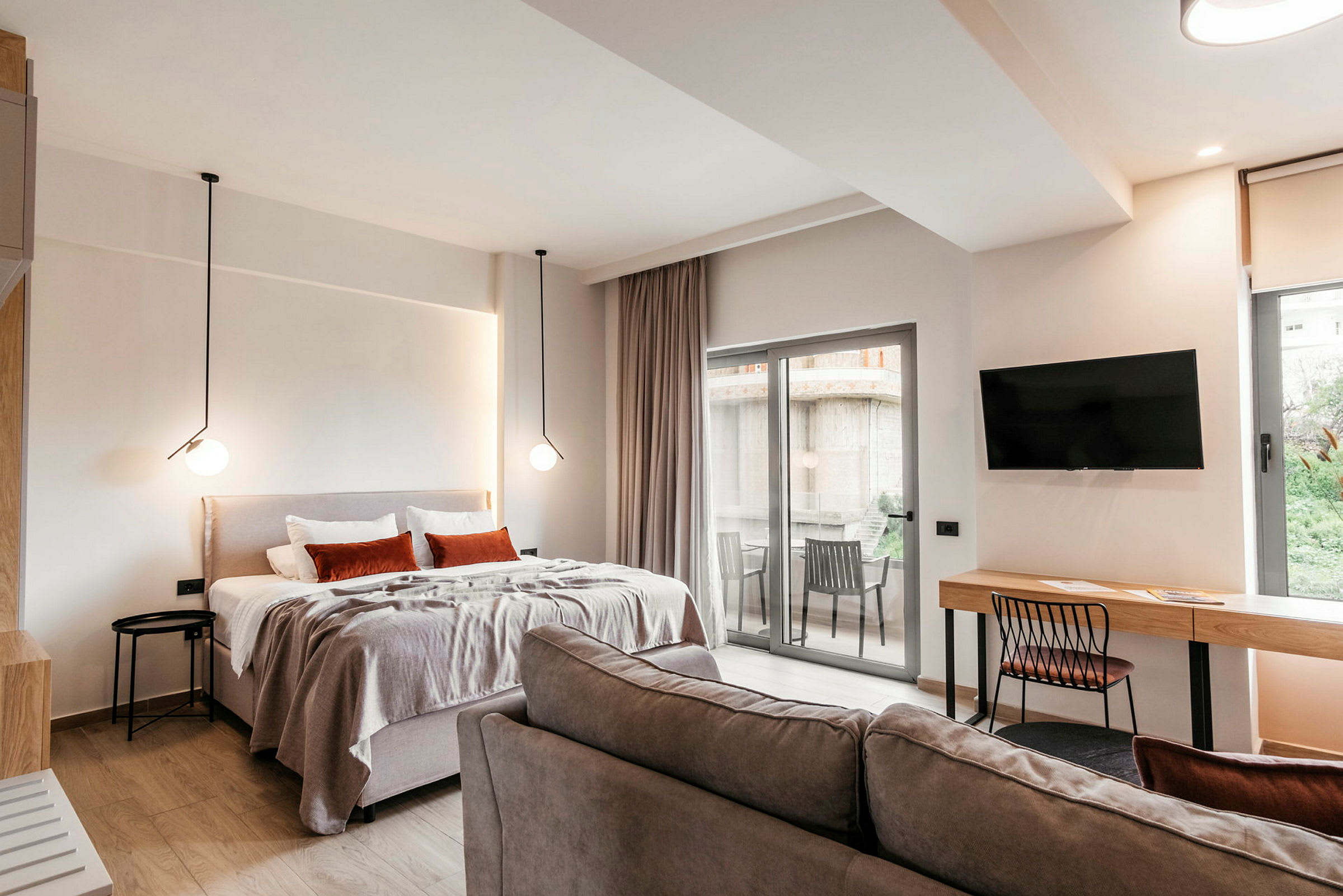 Ett modernt hotellrum med säng, soffa, skrivbord, TV och en balkong med utsikt. (AI-genererad text)