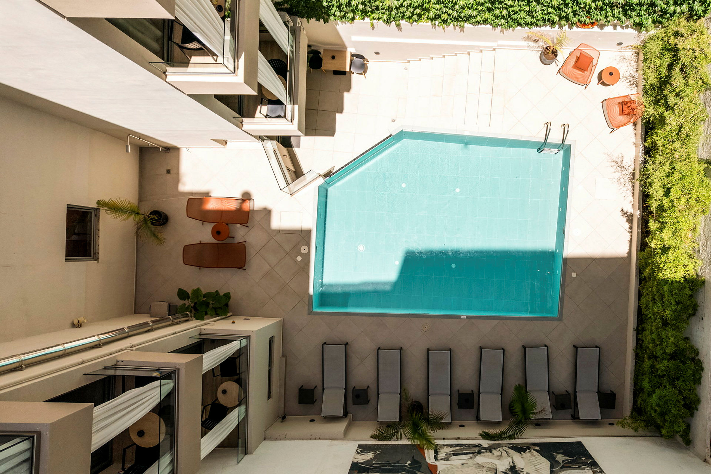 En innergård med en pool, solstolar och växtdekorationer. (AI-genererad text)