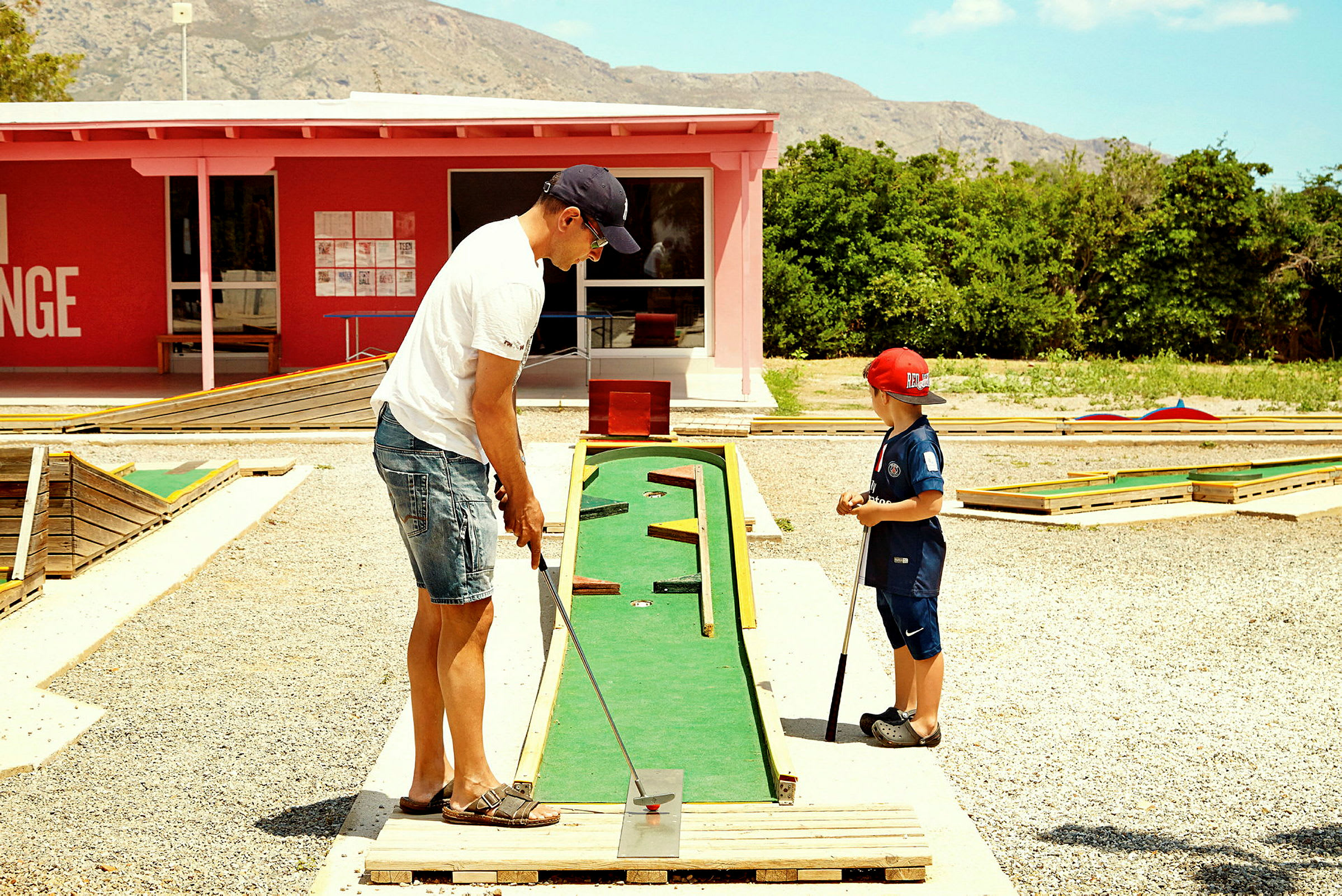 Två personer spelar minigolf på en bana utomhus. (AI-genererad text)