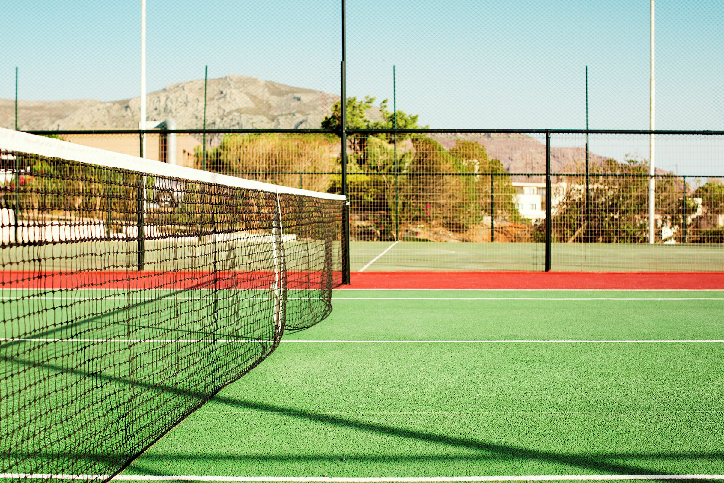 En tennisbana med nät och stängsel. (AI-genererad text)