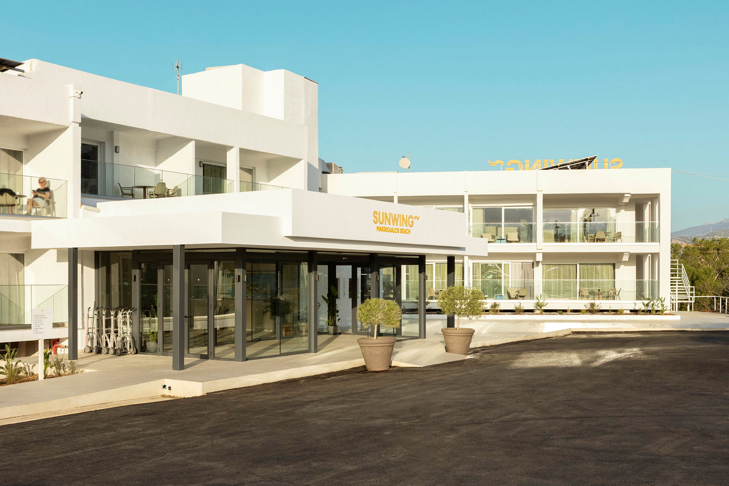 Fasad av ett modern hotellkomplex med vita väggar och gångväg framför. (AI-genererad text)