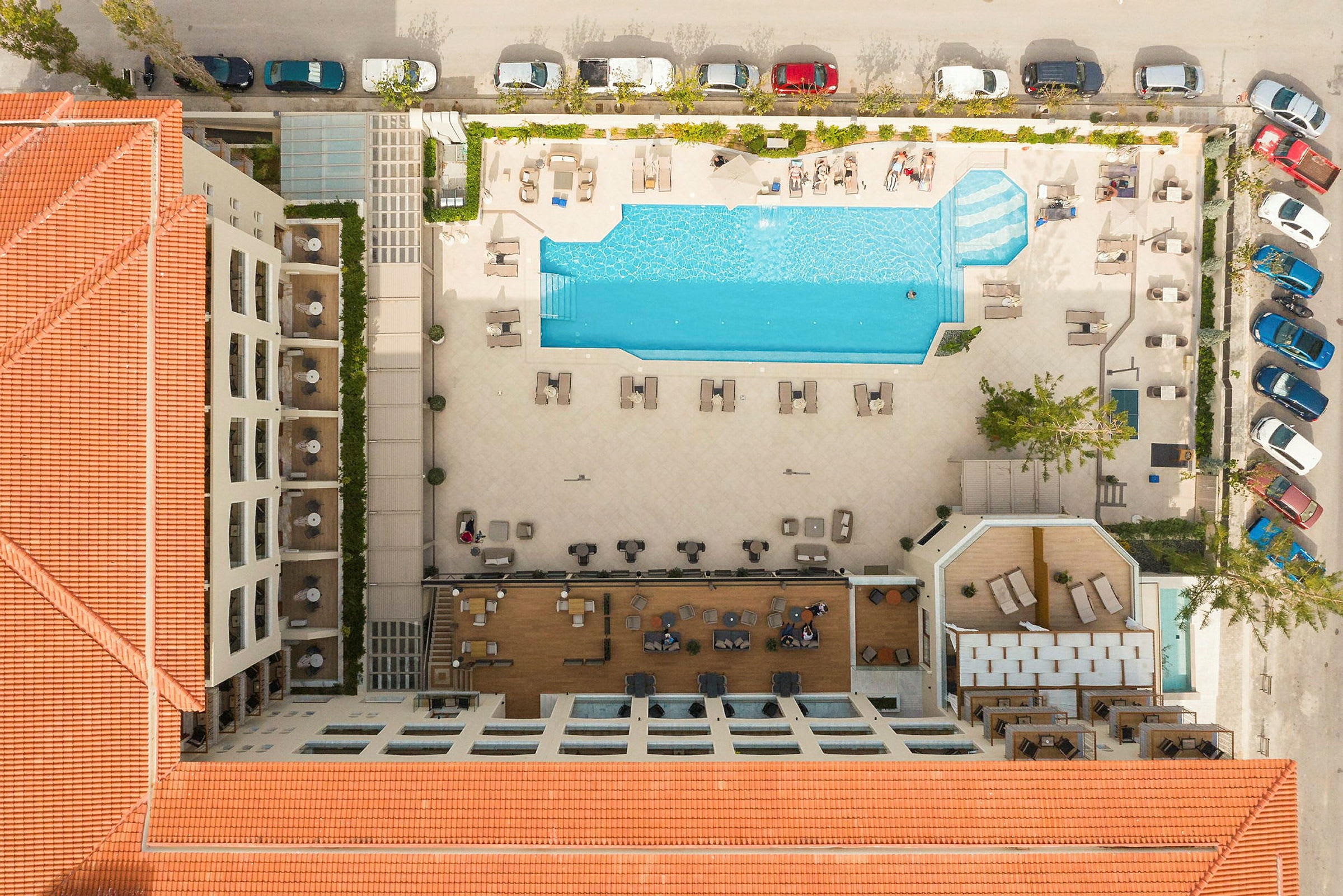Luftvy över hotell på en ort, med en stor pool och solstolar. (AI-genererad text)