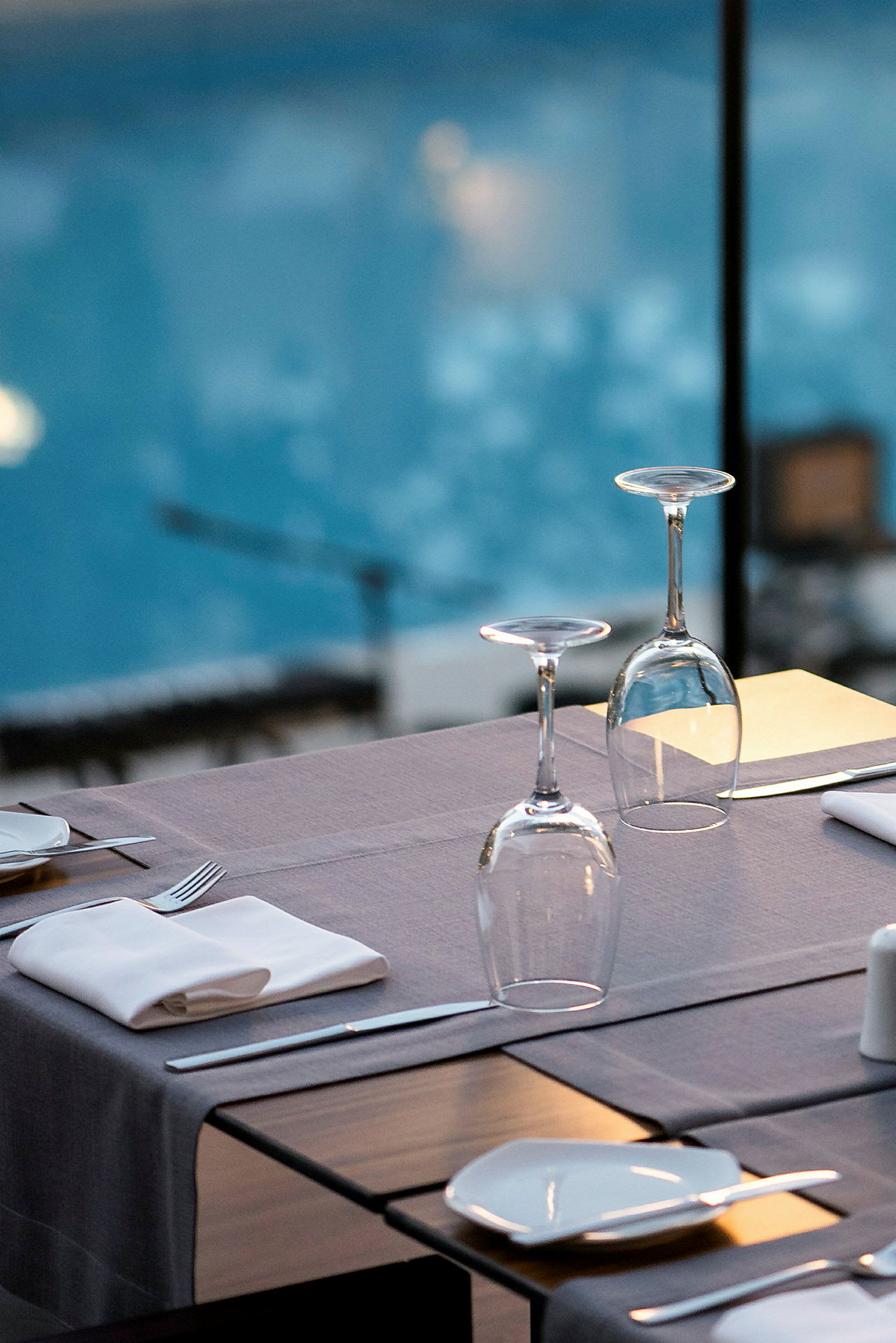 Ett dukat bord vid sidan av en swimmingpool, med glas och porslin. (AI-genererad text)