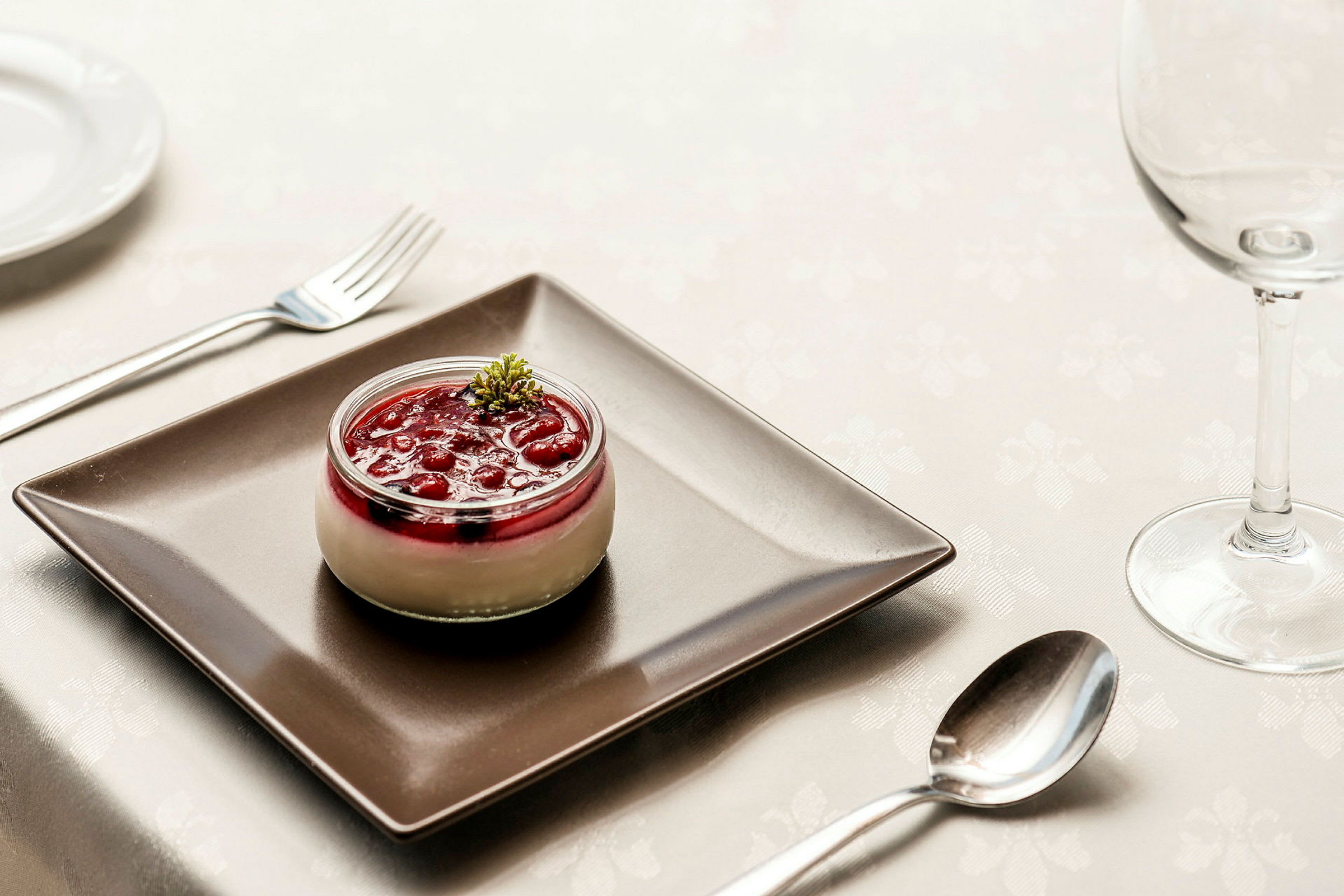 Dessert i glas med röda bär och grädde, serverad på svart tallrik. (AI-genererad text)
