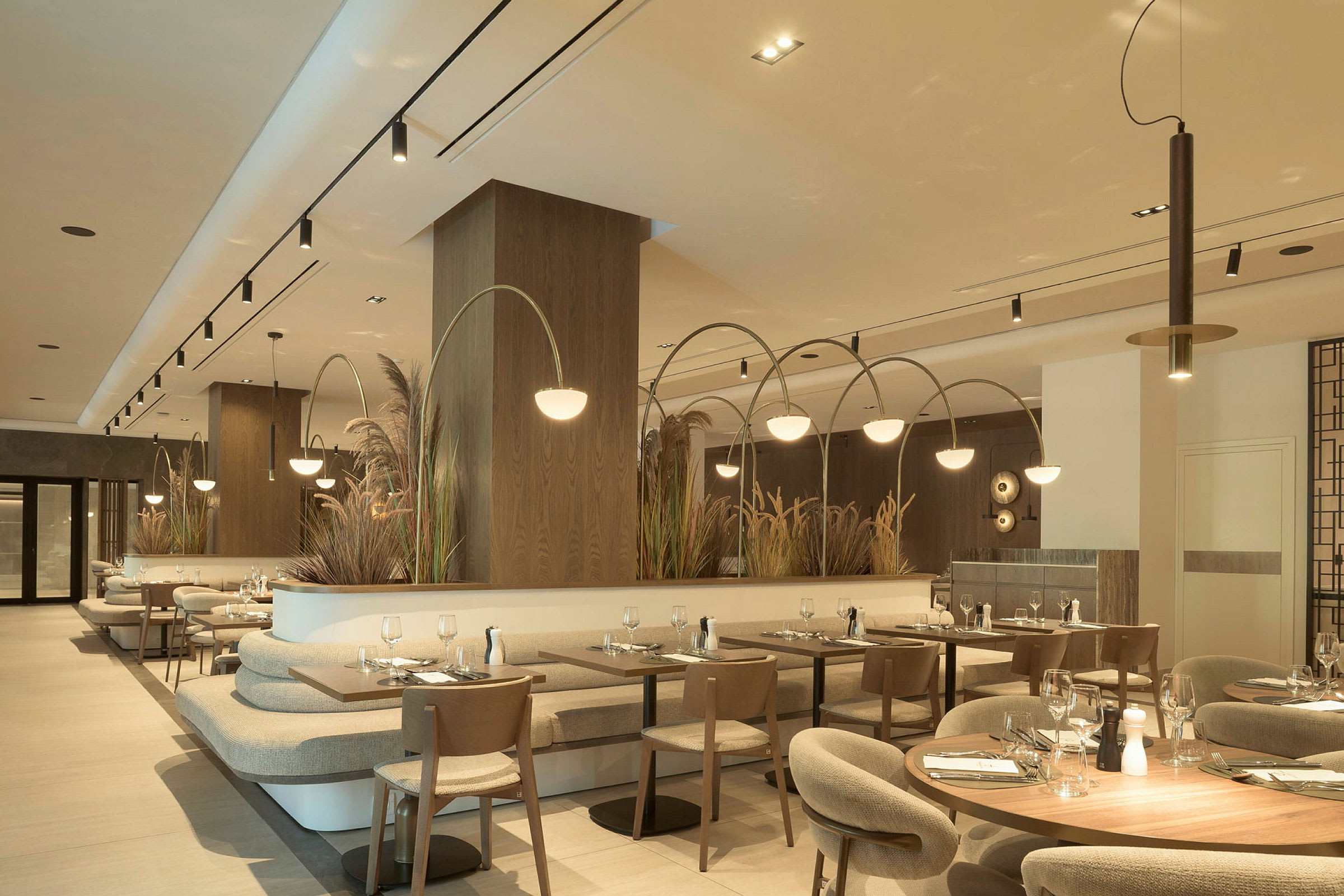 Interiör av en modern restaurang med flera bord och stolar, ljus belysning och dekorativa växter. (AI-genererad text)