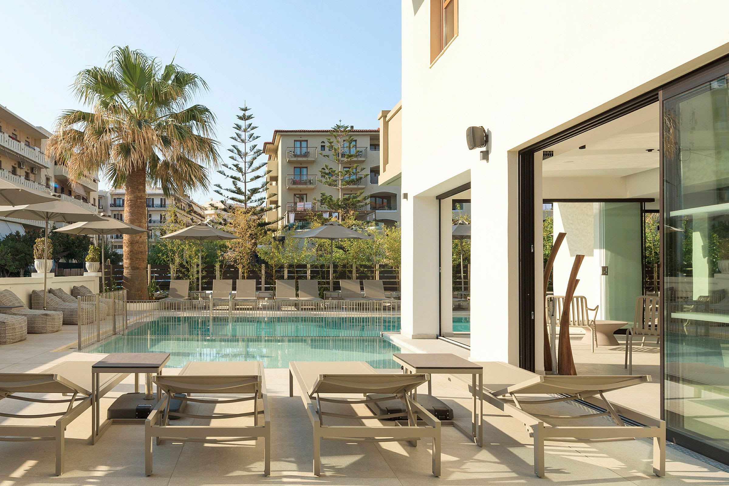 Utomhuspool med solstolar, parasoller och palmer vid ett hotell. (AI-genererad text)