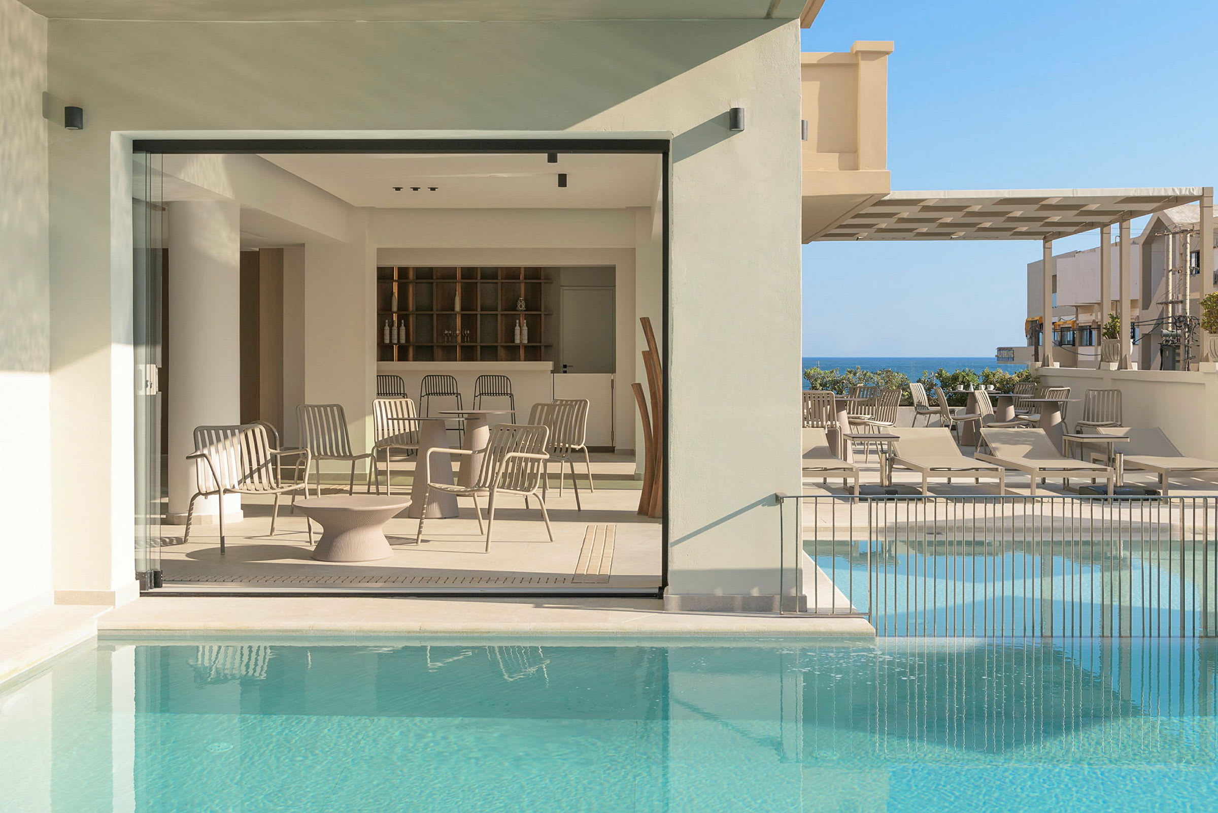 Modernt inredd terrass med pool, sittplatser och utsikt mot havet. (AI-genererad text)