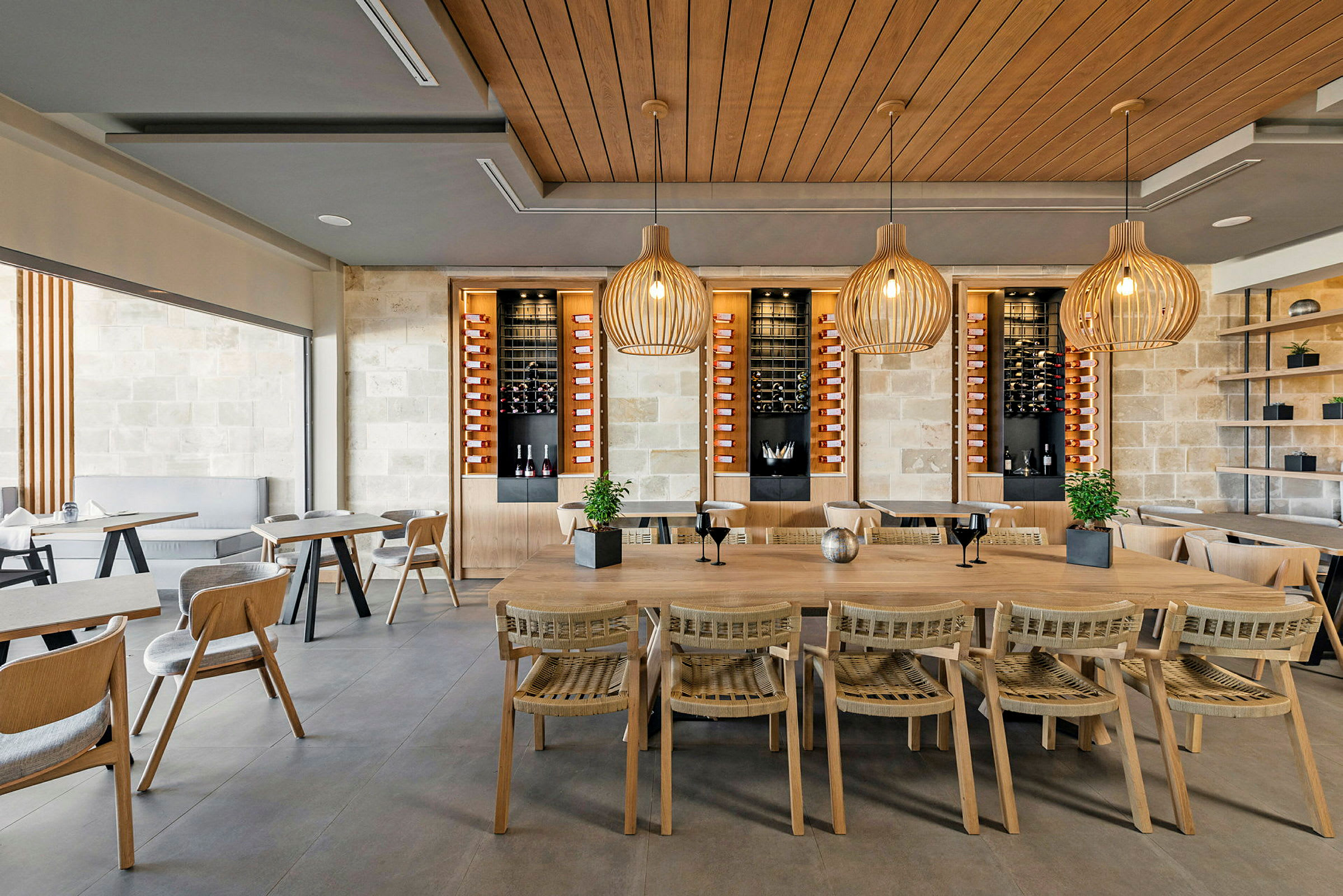 Interiör av en modern restaurang med trästolar och bord, samt dekorativa lampor i taket. (AI-genererad text)