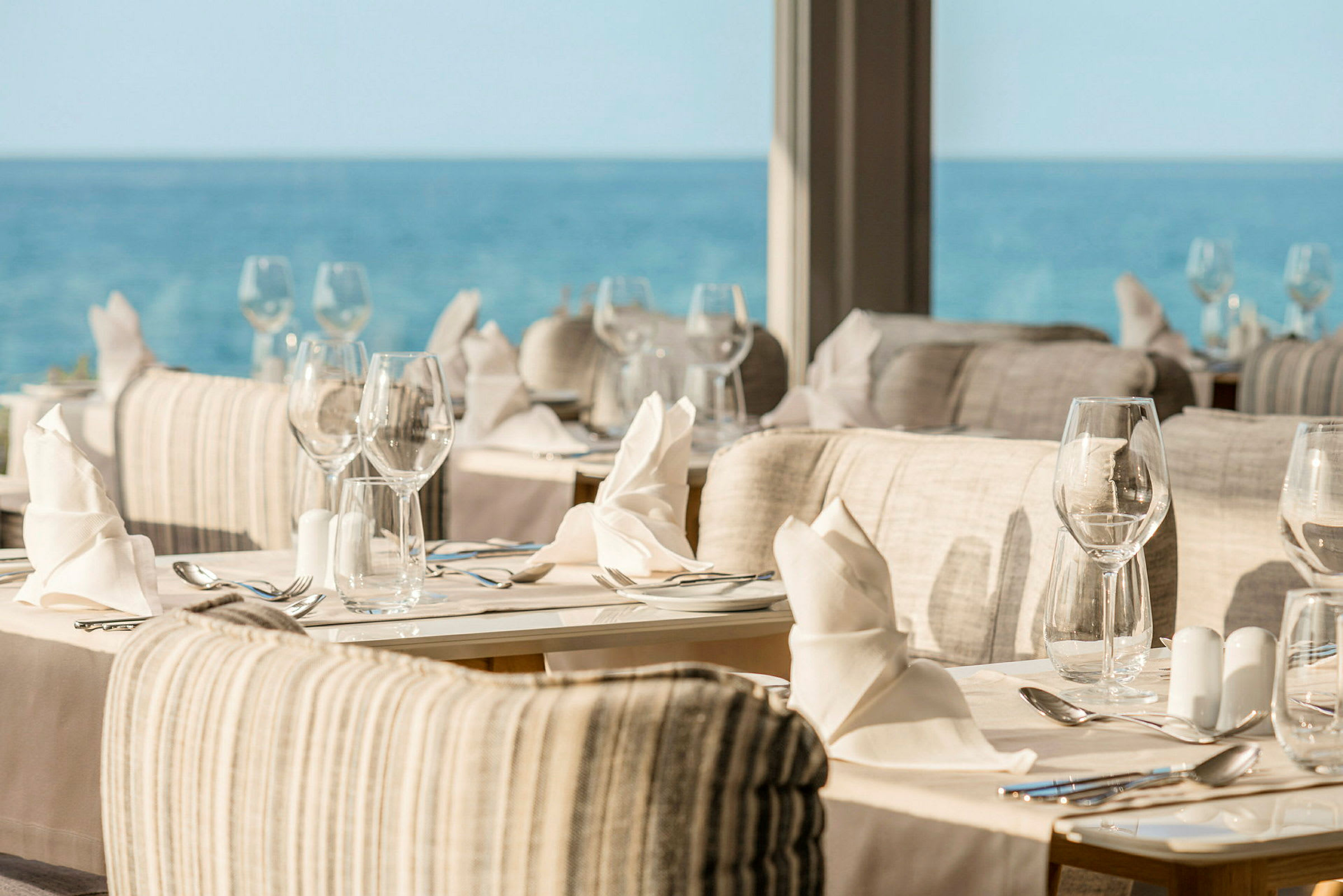 Restaurang med dukade bord och utsikt över havet. (AI-genererad text)