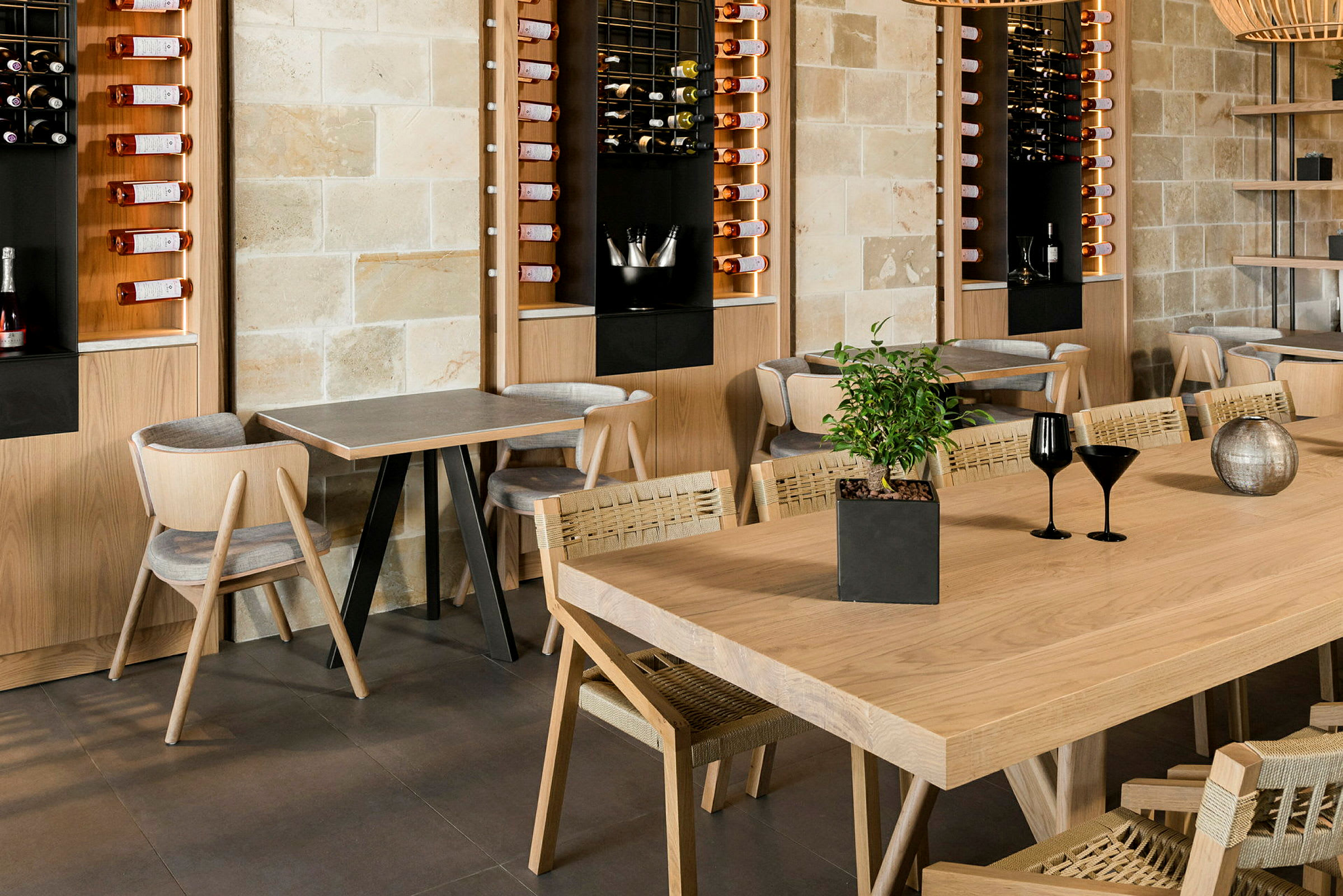 En modern restaurang med träbord och stolar samt väggförvaring för vinflaskor. (AI-genererad text)