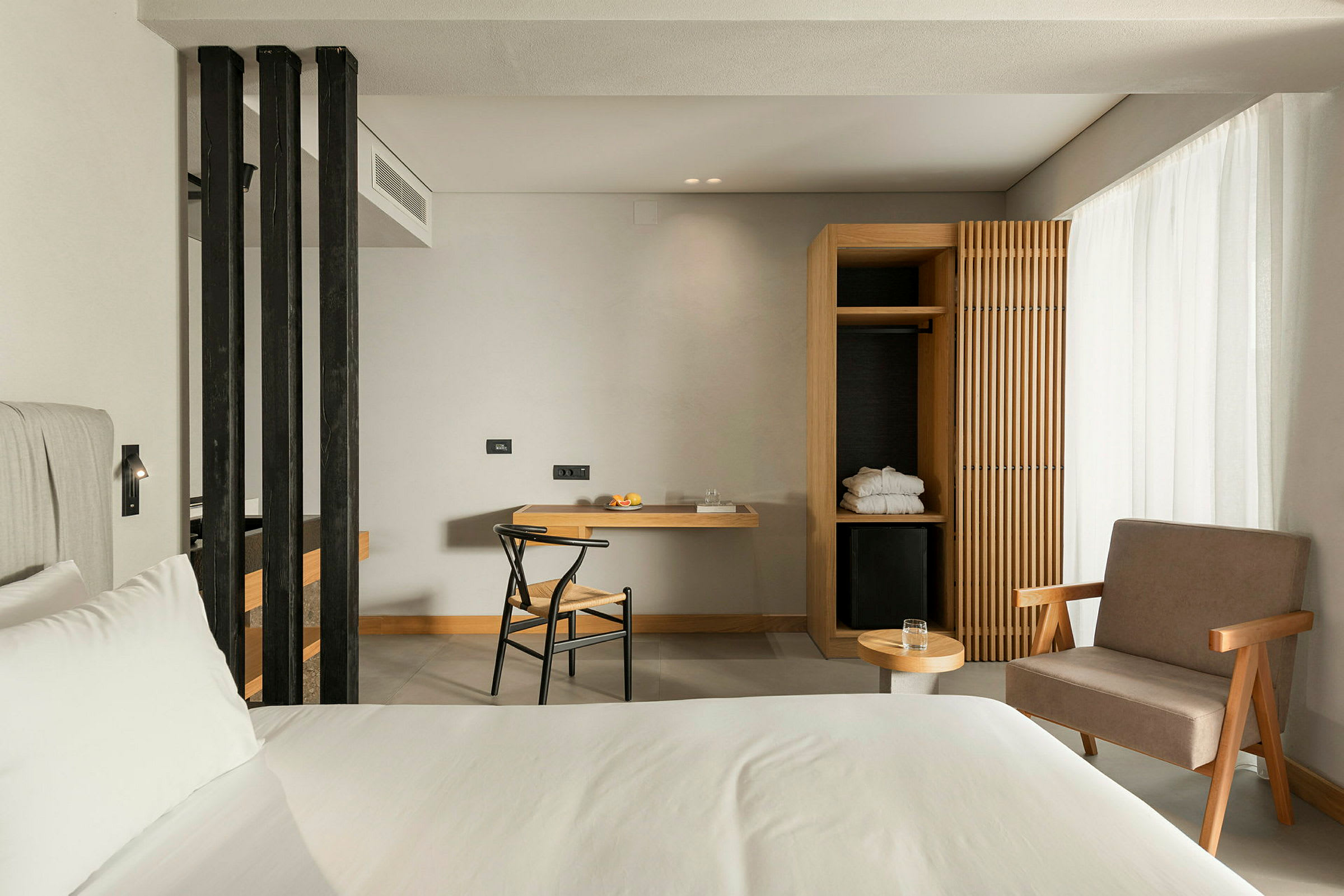 Ett modernt hotellrum med en säng, en arbetsplats med stol, och en öppen garderob. (AI-genererad text)