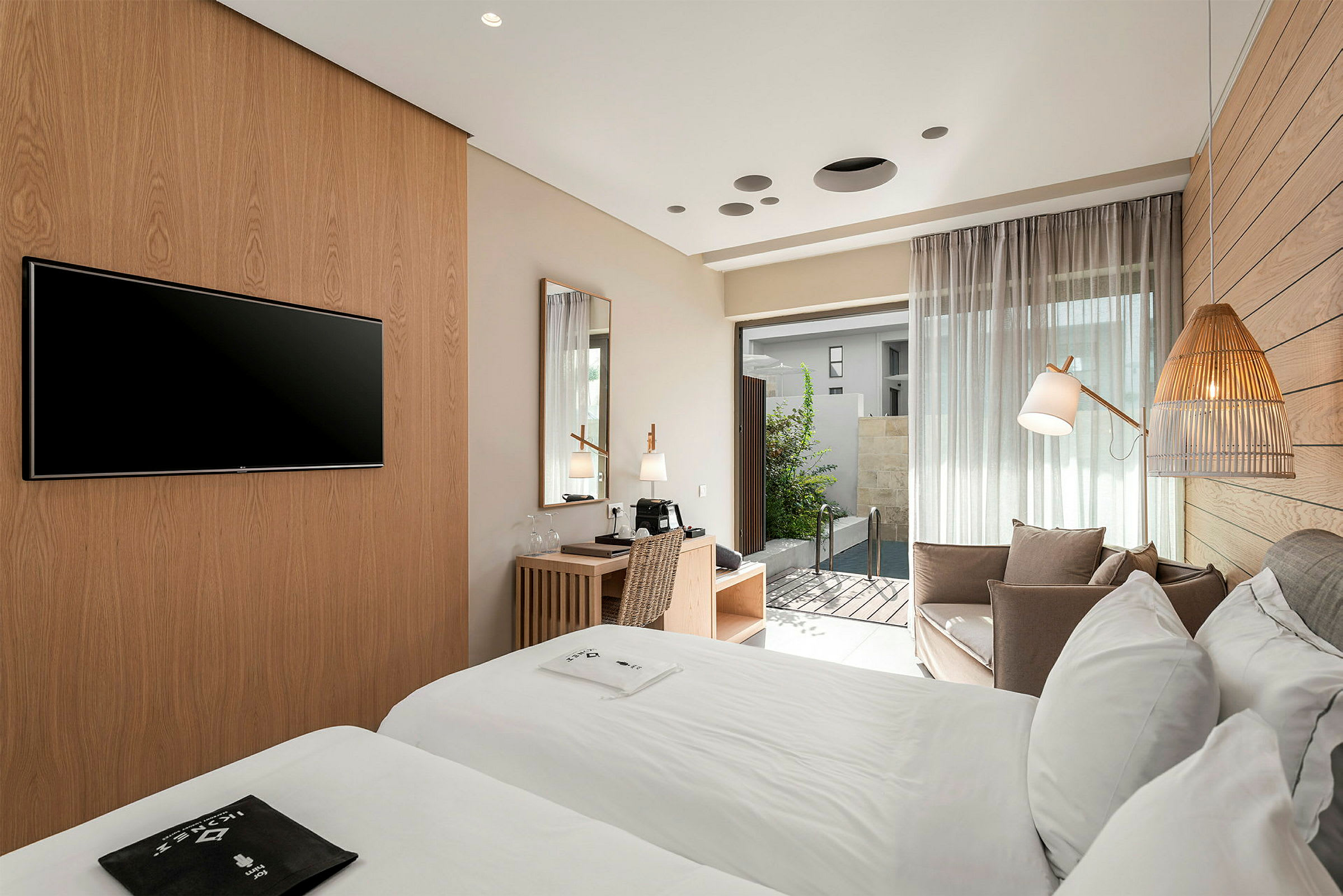 Hotellrum med två sängar, skrivbord och sittgrupp. Dörr som leder ut till liten pool. (AI-genererad text)