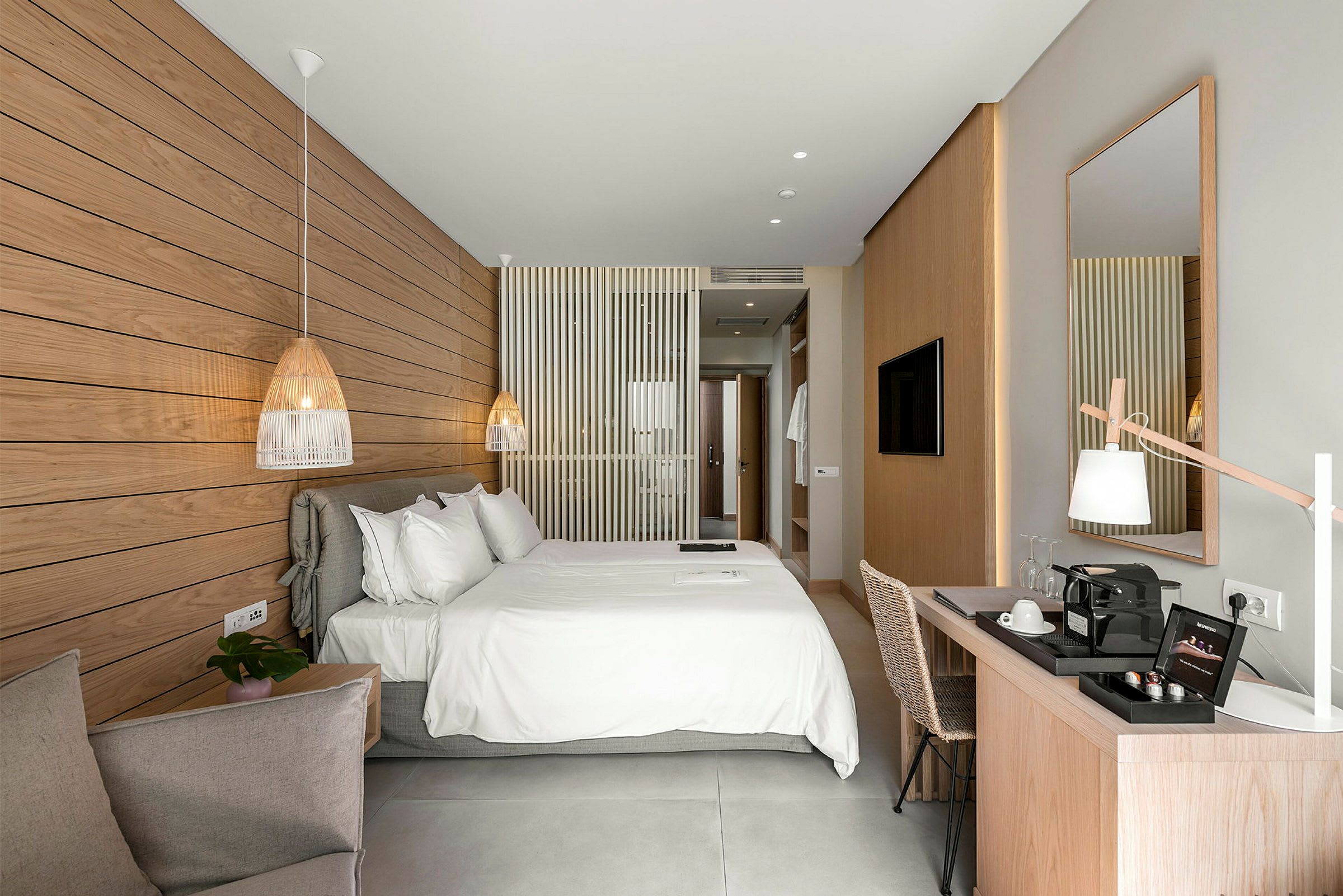 Ett ljus och modernt hotellrum med en stor dubbelsäng, en skrivbordsplats och en dekorativ marmorpanel på väggen. (AI-genererad text)