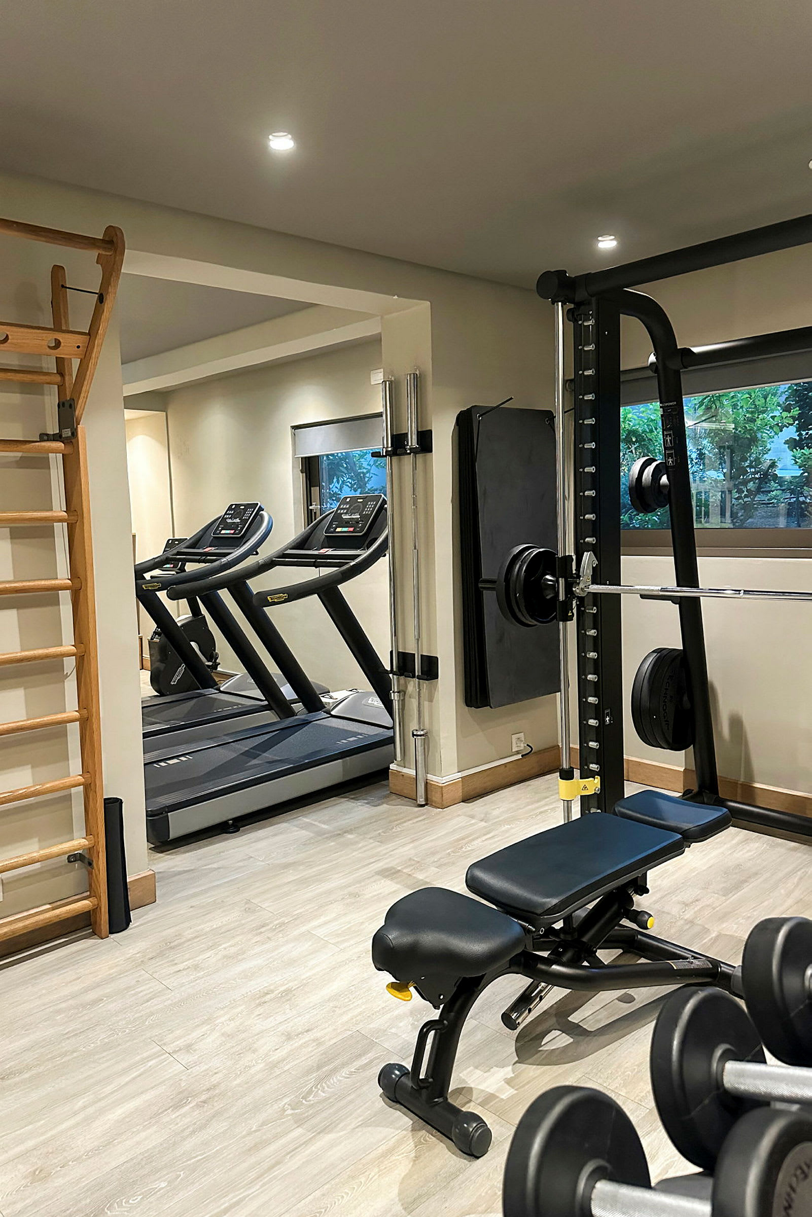 Ett gym med träningsutrustning, inklusive löpband, vikter och en träningsbänk. (AI-genererad text)