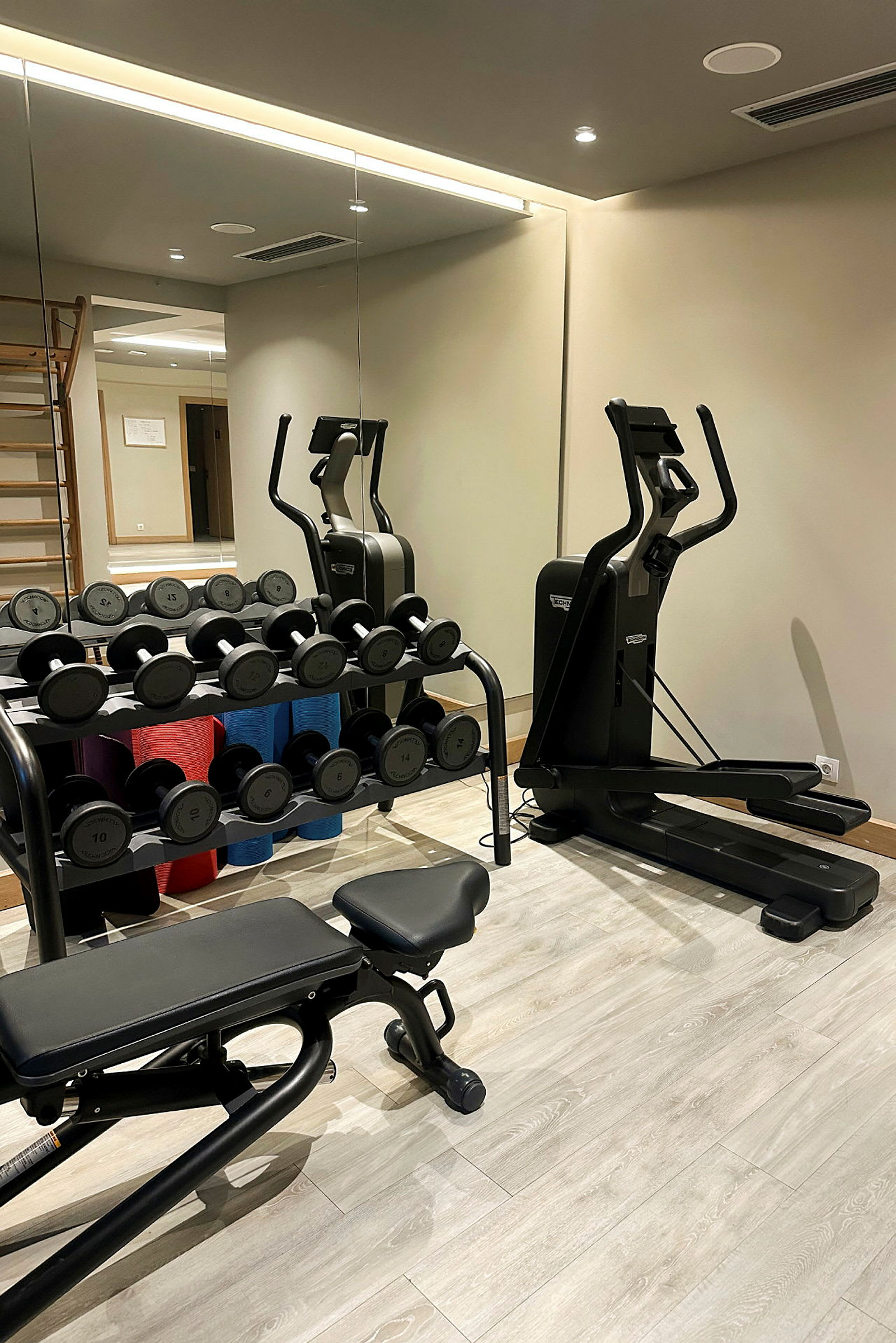 Gymrum med träningsmaskin, hantlar och bänk. (AI-genererad text)