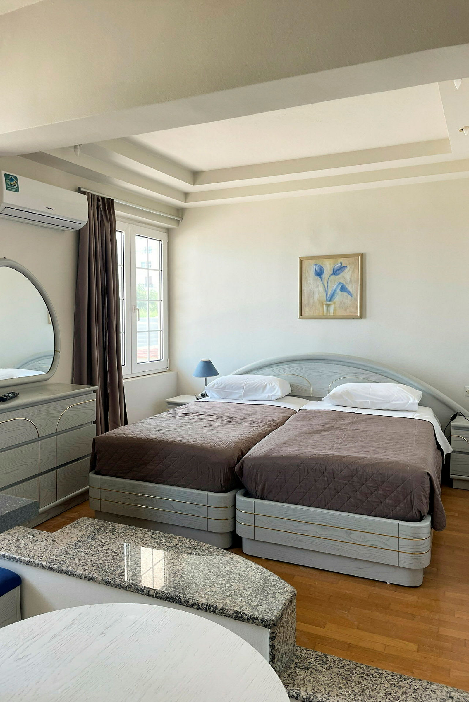 Hotellrum med två enkelsängar, ett skrivbord och en spegel. (AI-genererad text)