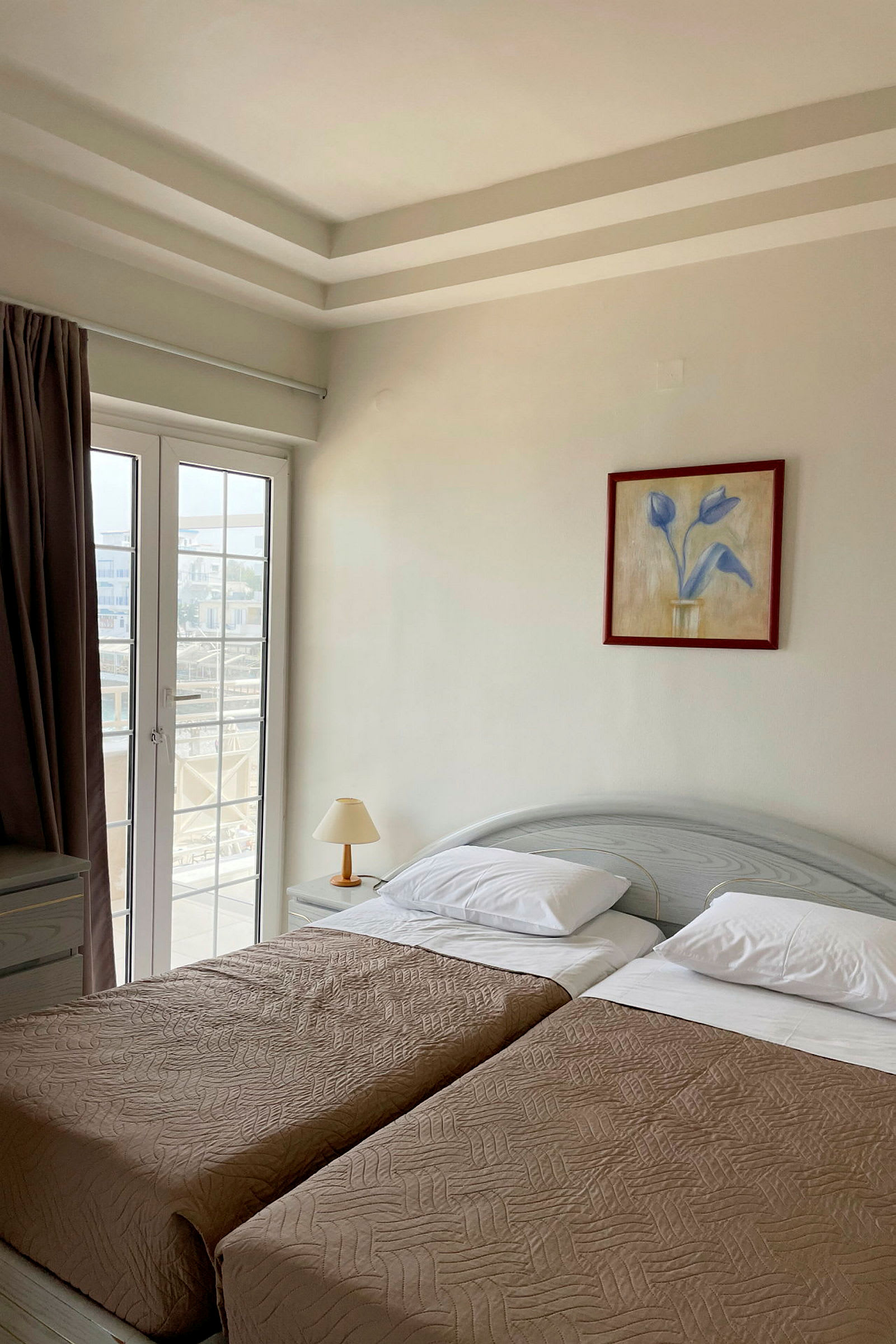 Ett hotellrum med två enkelsängar, en lampa och en glasdörr. (AI-genererad text)