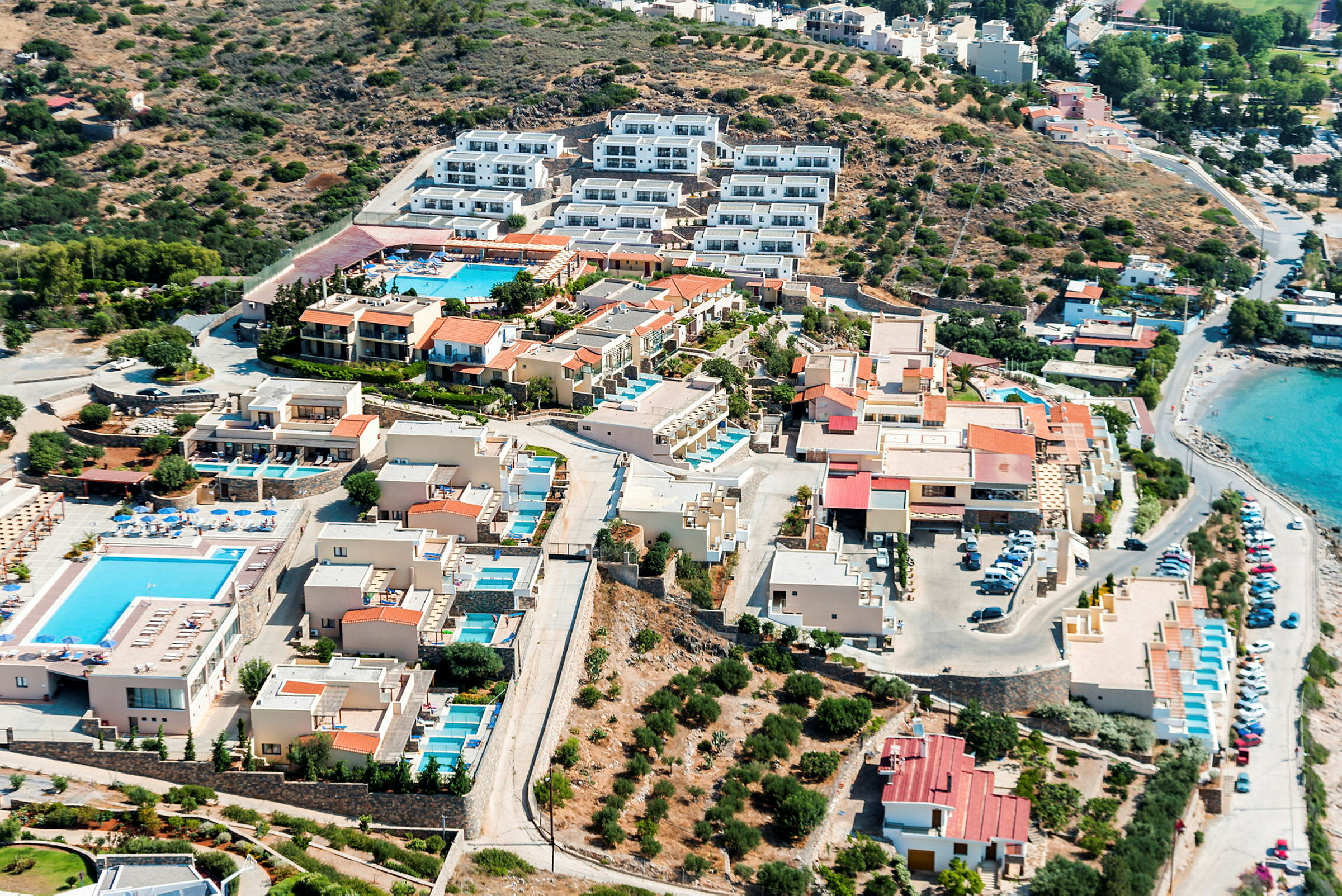 Flygfoto över hotellområde med pooler och strand. (AI-genererad text)