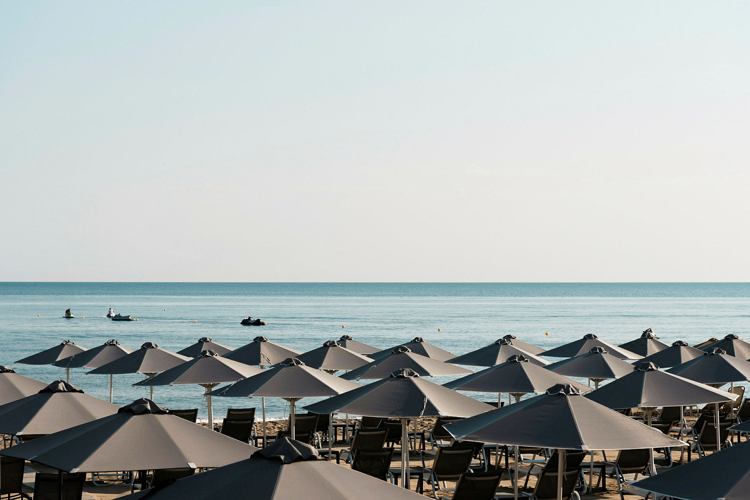 Strand med solstolar och parasoller samt havet i bakgrunden. (AI-genererad text)