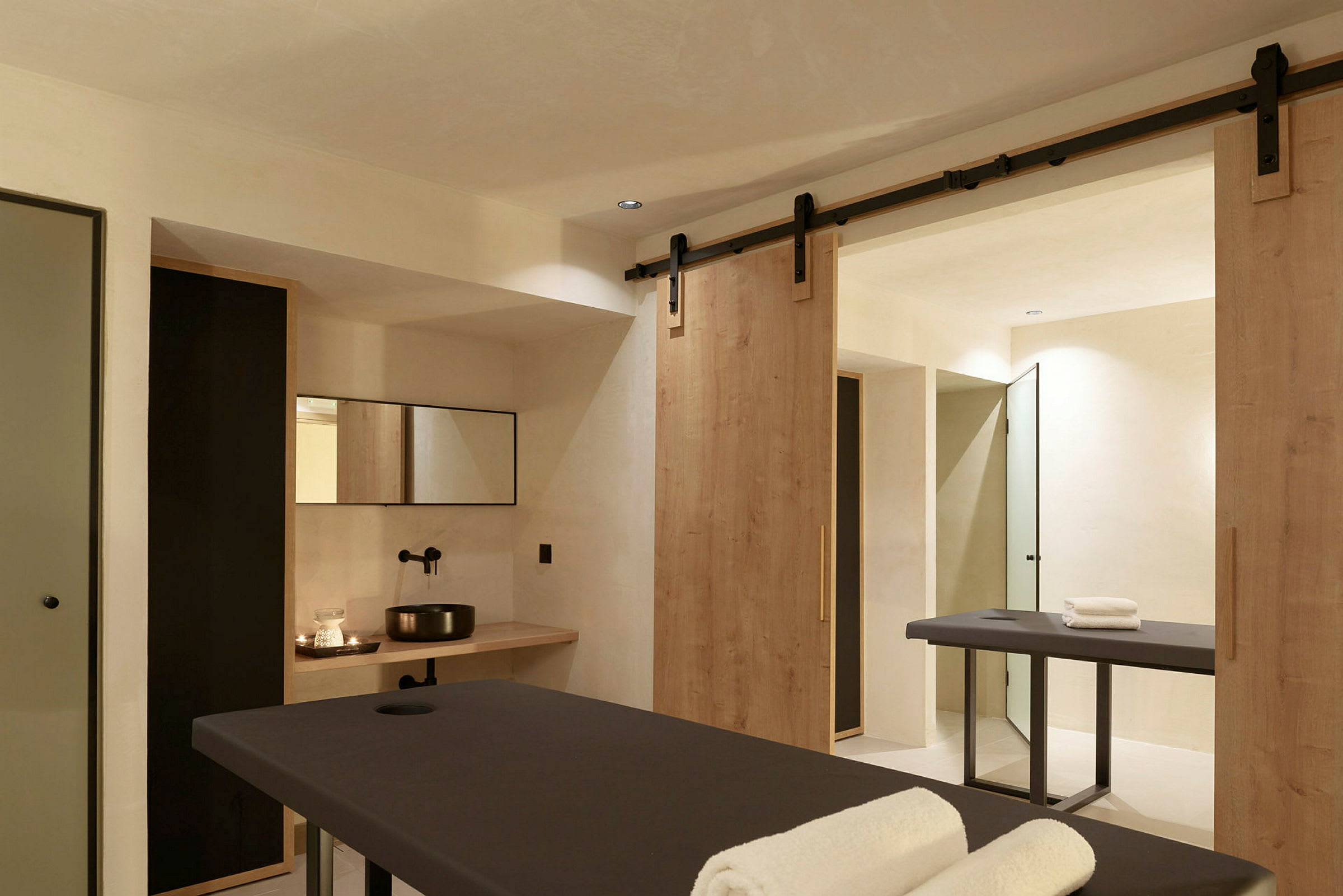 Ett spa-rum med två massagebänkar och en disk med handfat. (AI-genererad text)