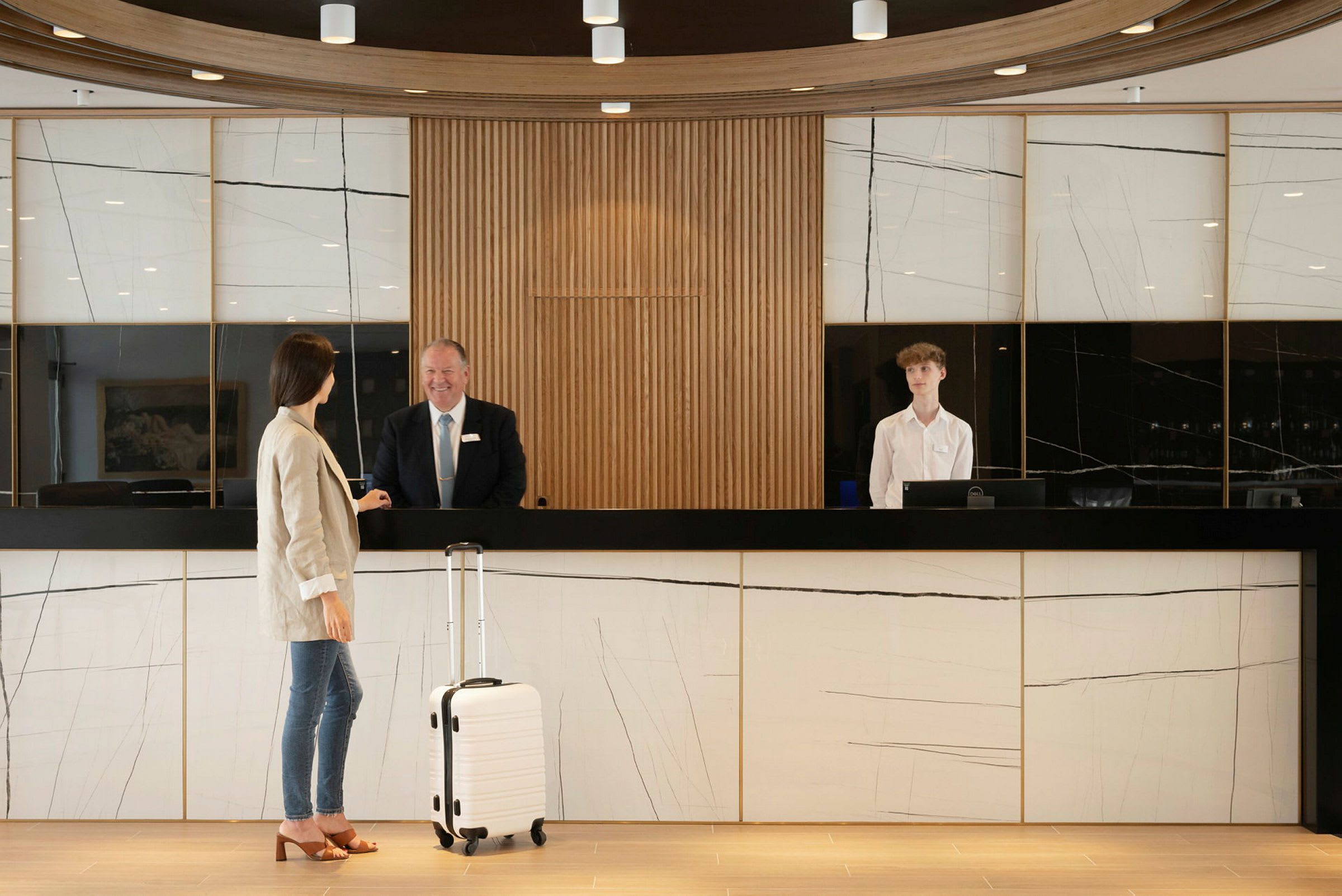 Reception med marmorpaneler och en gäst med resväska. (AI-genererad text)