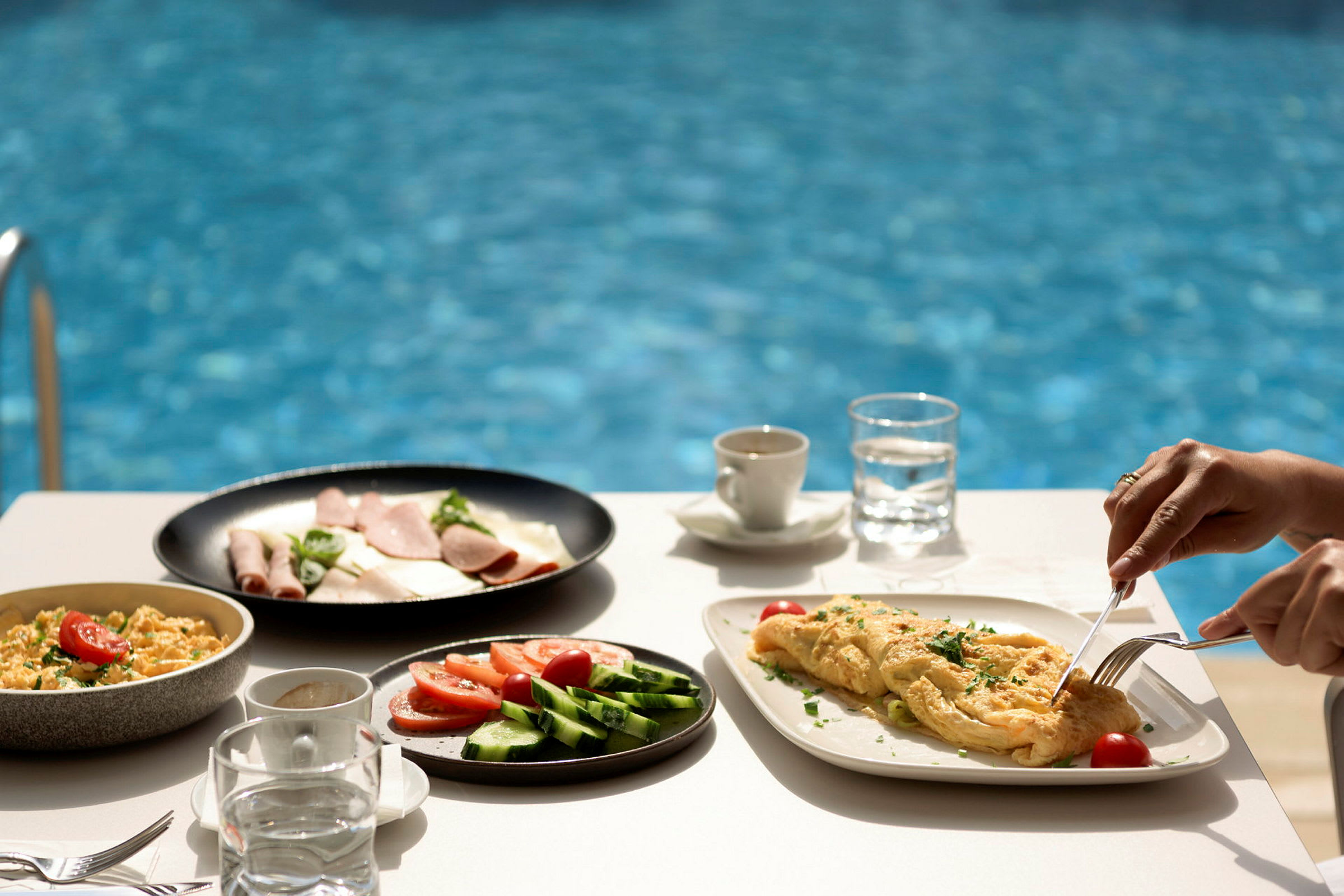 Frukost vid en pool, med omelett och grönsaker på tallrik. (AI-genererad text)
