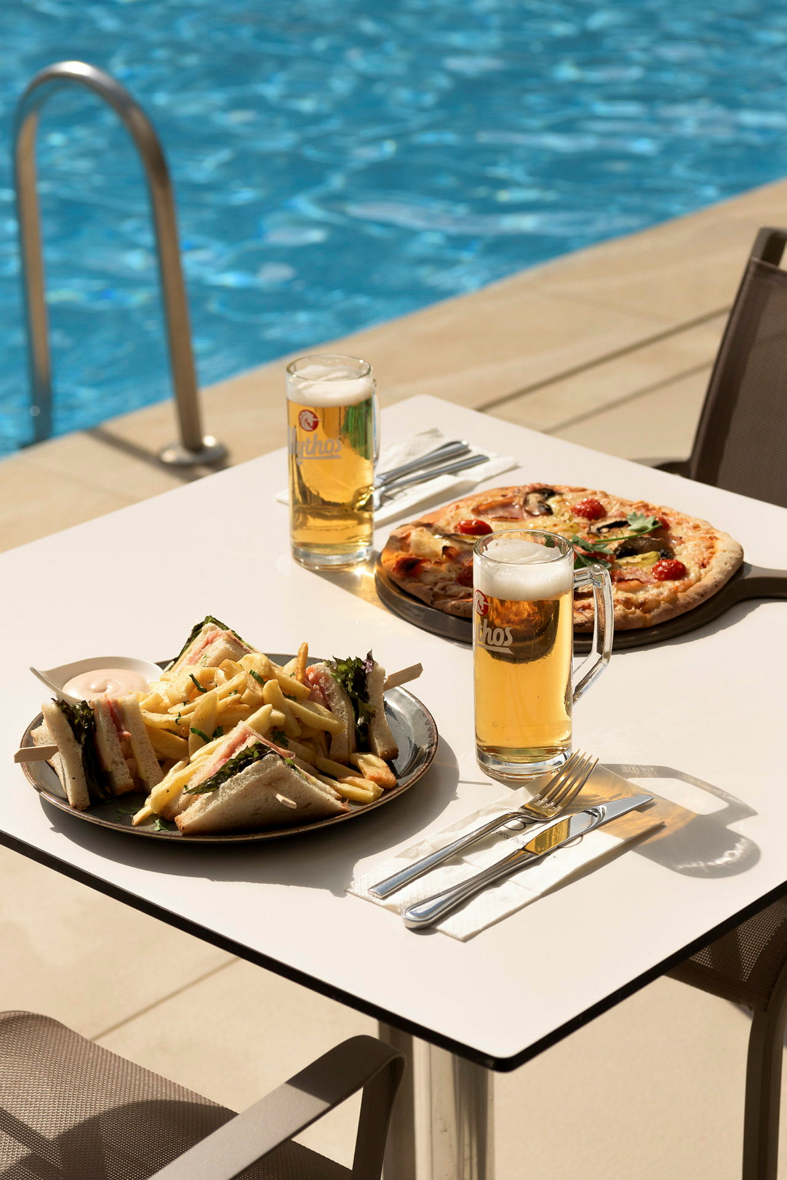 Ett bord med mat och dryck vid sidan av en pool. (AI-genererad text)