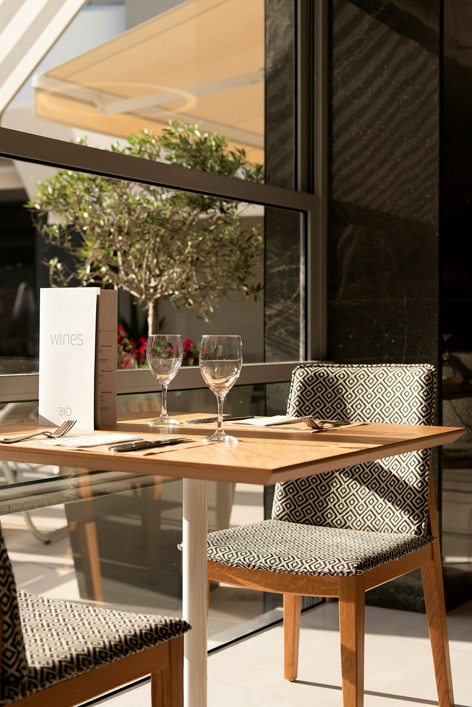 Ett dukat bord med två glas och meny vid fönstret. (AI-genererad text)
