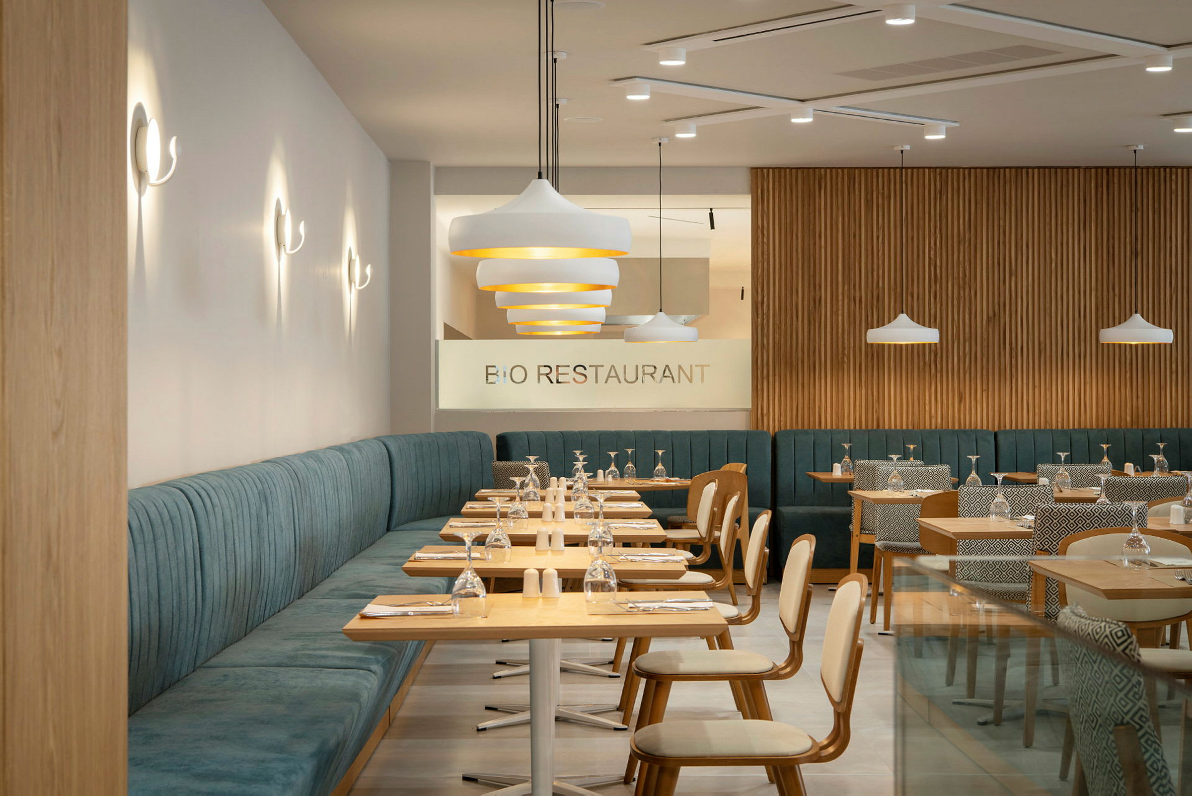 Modern restaurang med träbord och stoppade sittplatser. Glas och tallrikar är arrangerade på borden. (AI-genererad text)