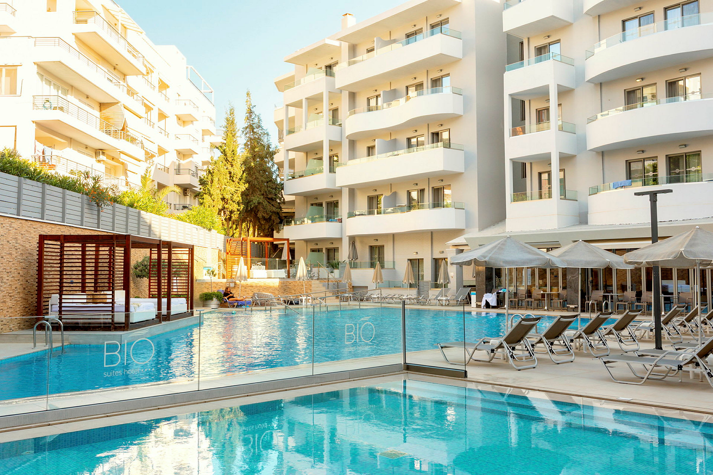 Bild av ett hotell med en utomhuspool och solstolar framför byggnaden. (AI-genererad text)
