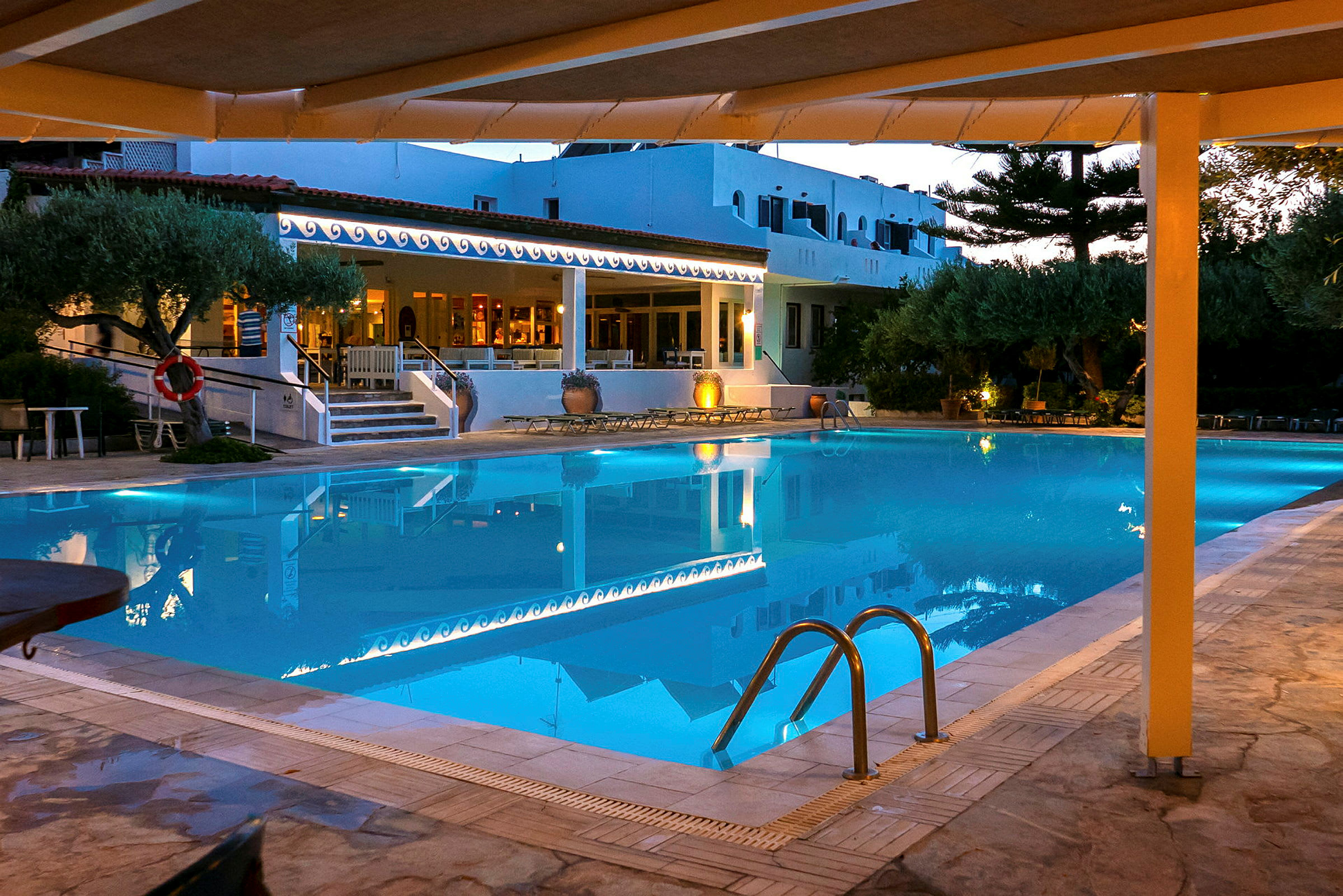 En upplyst pool vid ett hotell på kvällen. (AI-genererad text)